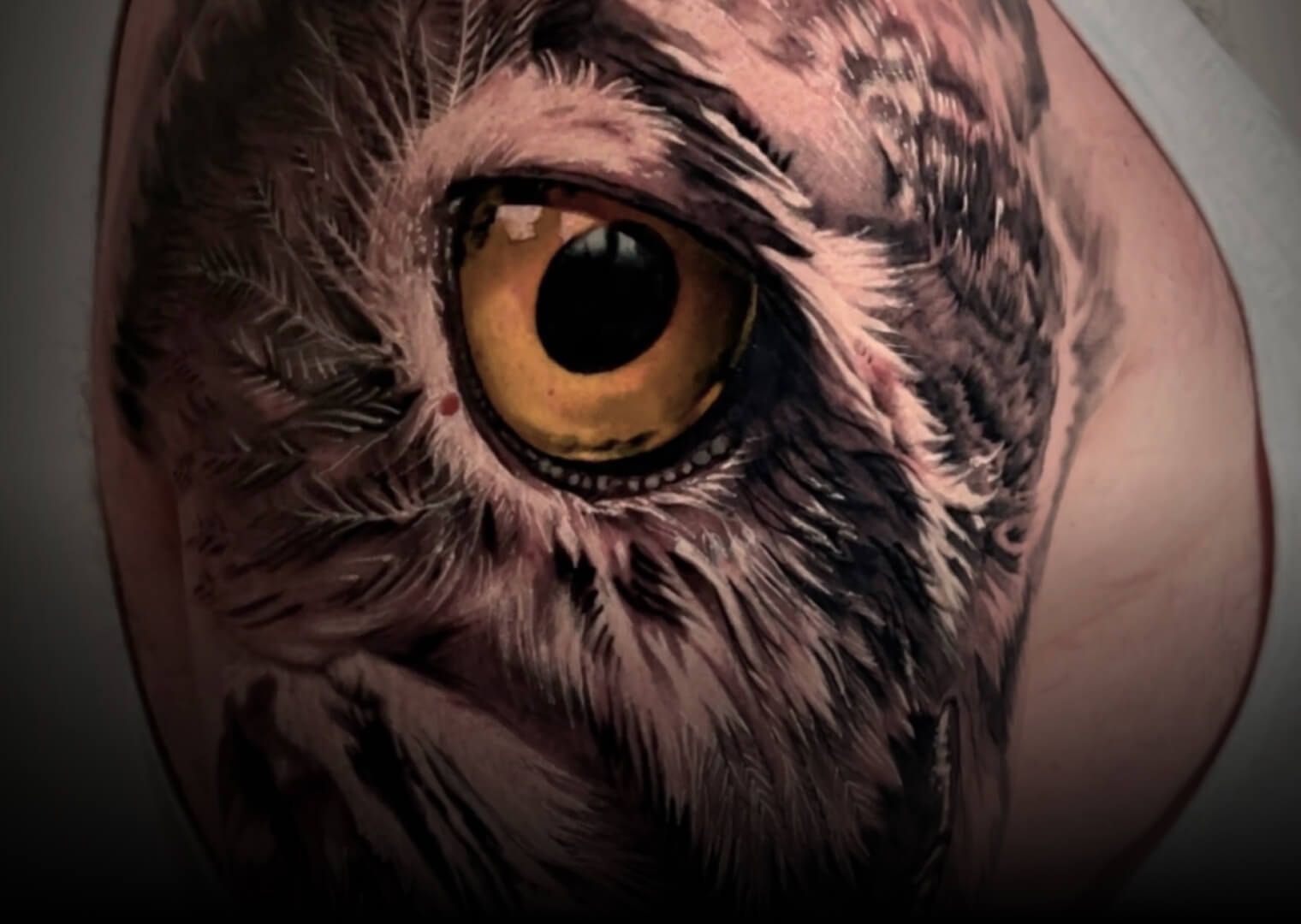 A close up of a tattoo of an owl 's eye