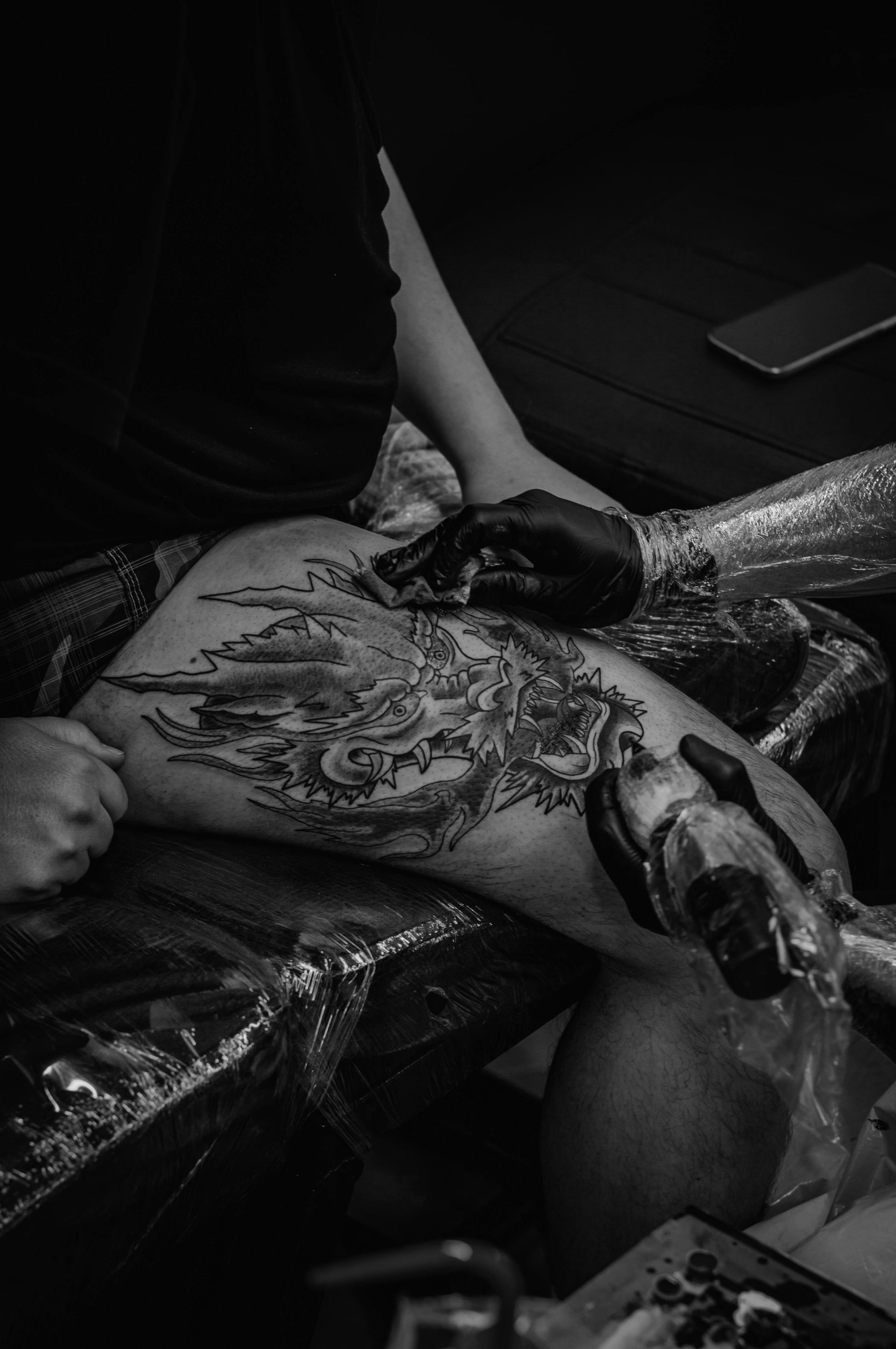 Schwarz-weißes Blumentattoo auf dem Arm einer Person, neben einem Button-Down-Hemd.