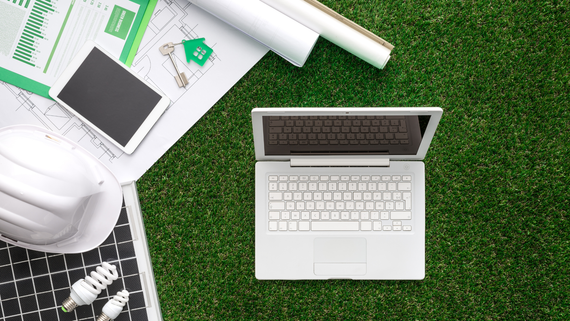 A laptop computer is sitting on top of a lush green field.