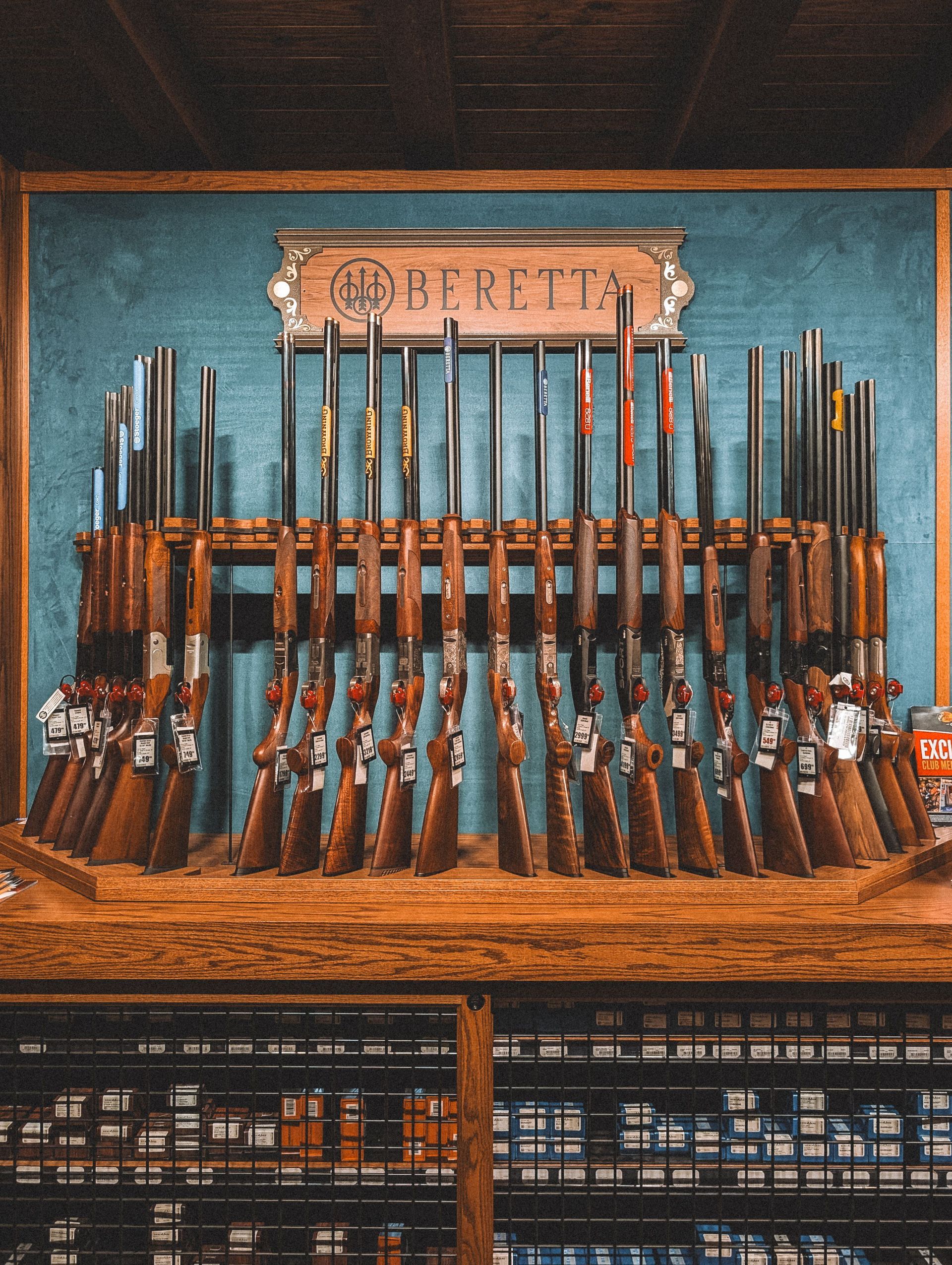 Rifle display on a wooden rack in a western-style storefront, with a sign above and shelves below