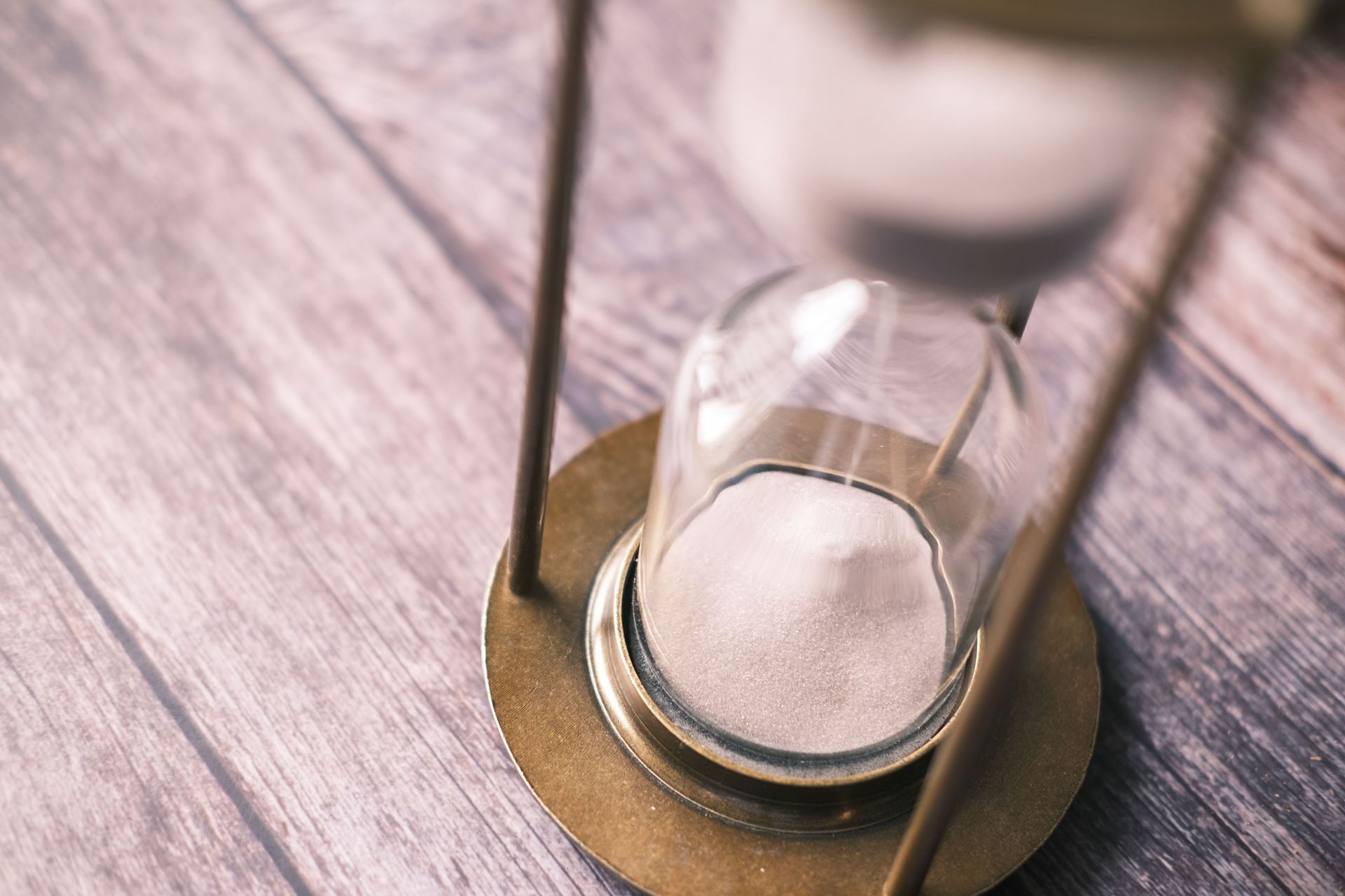 Glass hourglass with white sand on a wooden surface