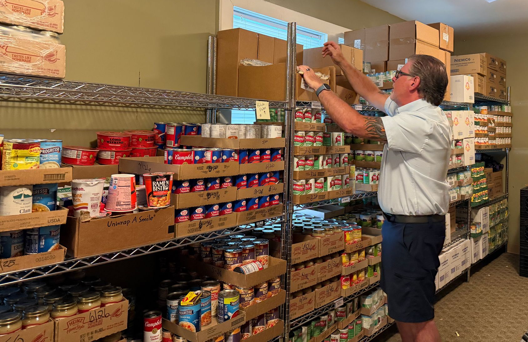 Person stocking food pantry shelf.