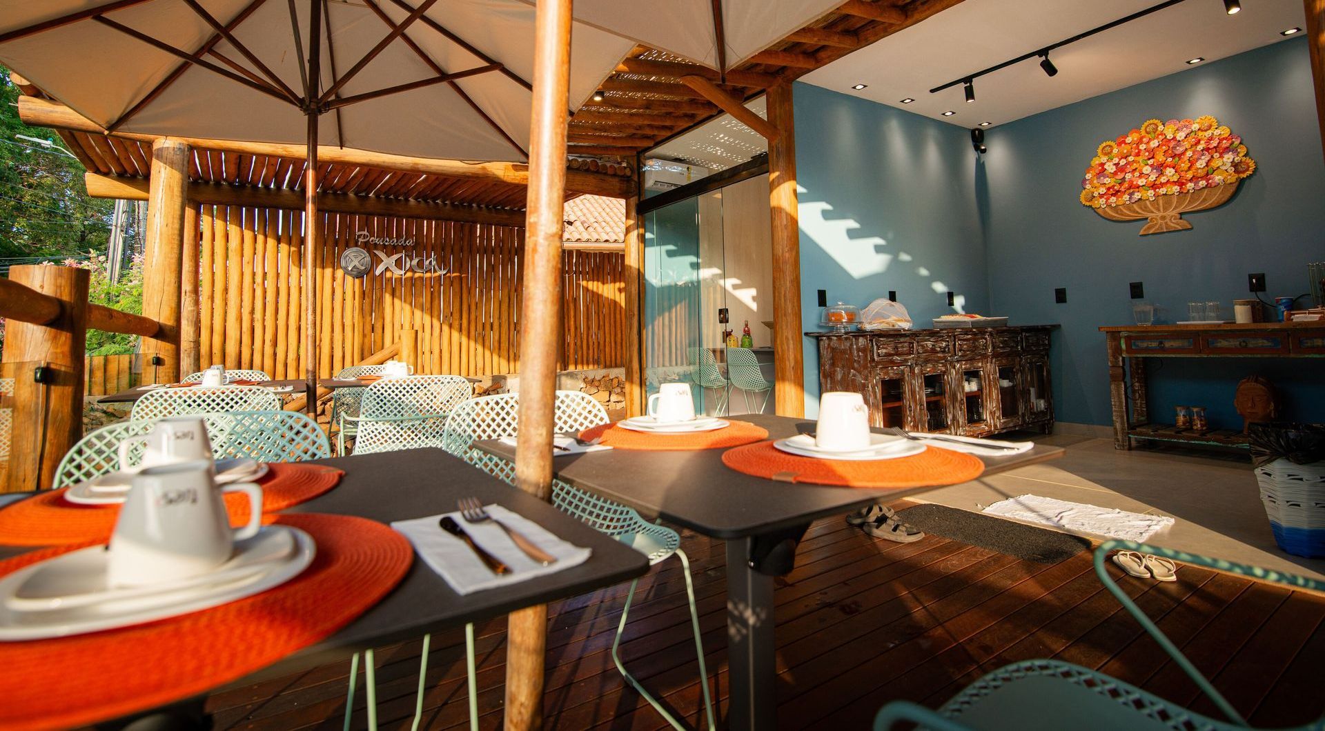 Um restaurante com mesas, cadeiras e guarda-sóis Pousada Xica