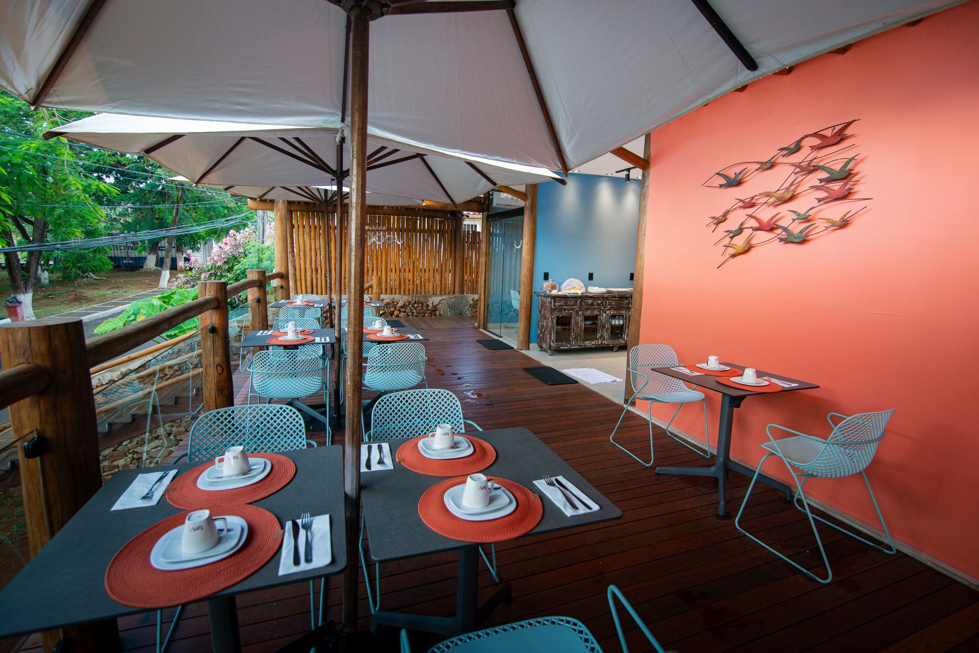 Um restaurante com mesas e cadeiras sob guarda-sóis Pousada Xica