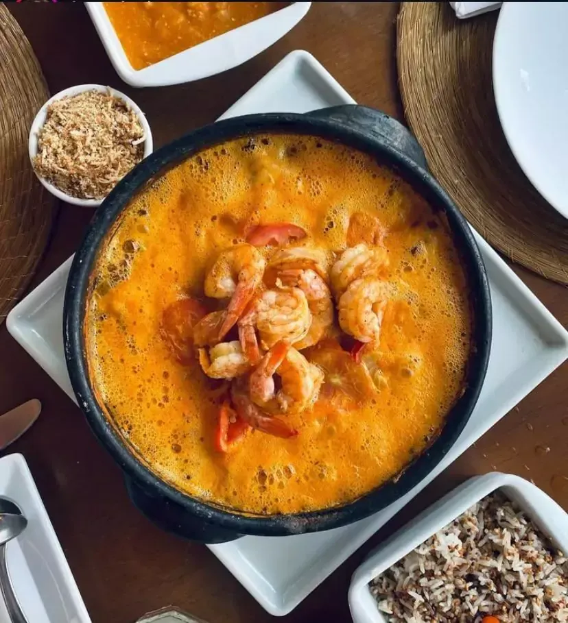 Uma tigela de sopa com camarão e arroz sobre uma mesa Pousada Xica