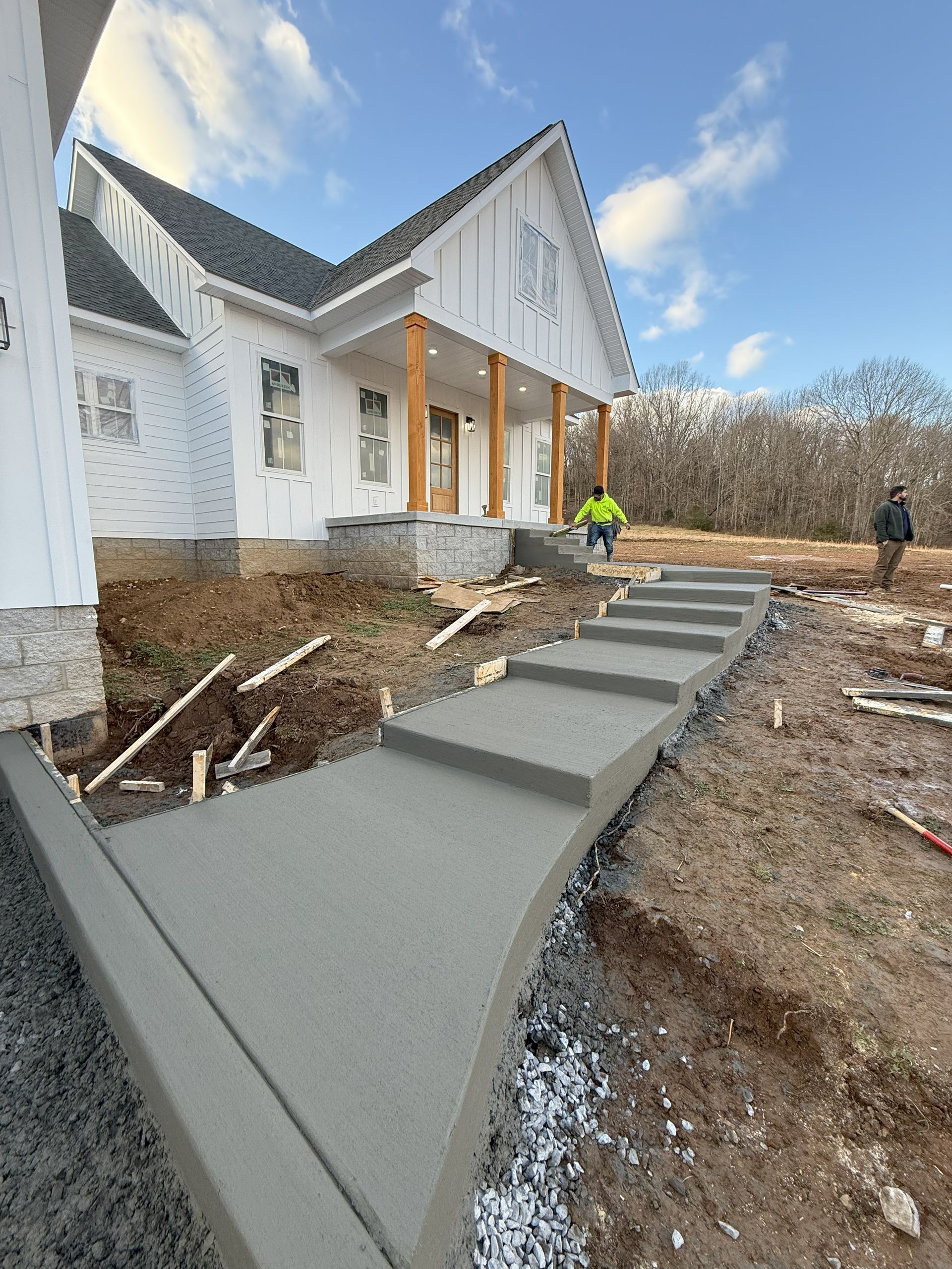 A concrete walkway is being built in front of a house.