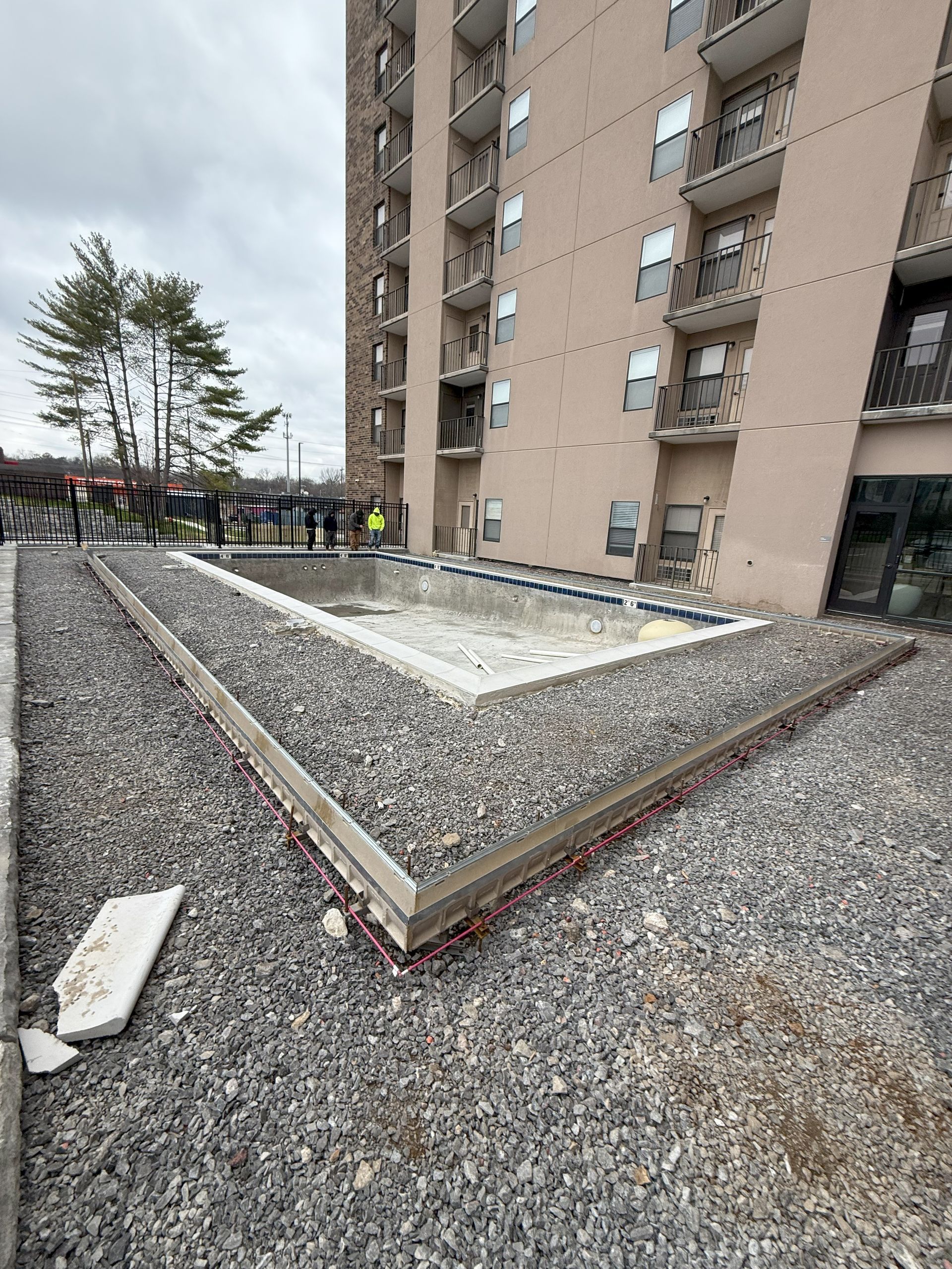 A swimming pool is being built in front of a tall building.