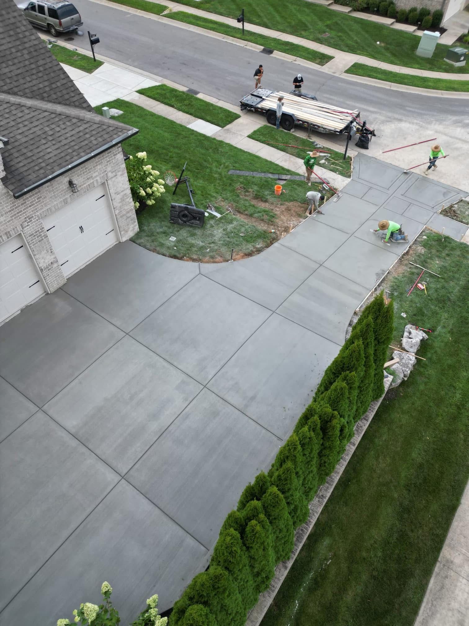 An aerial view of a concrete driveway being built in front of a house.