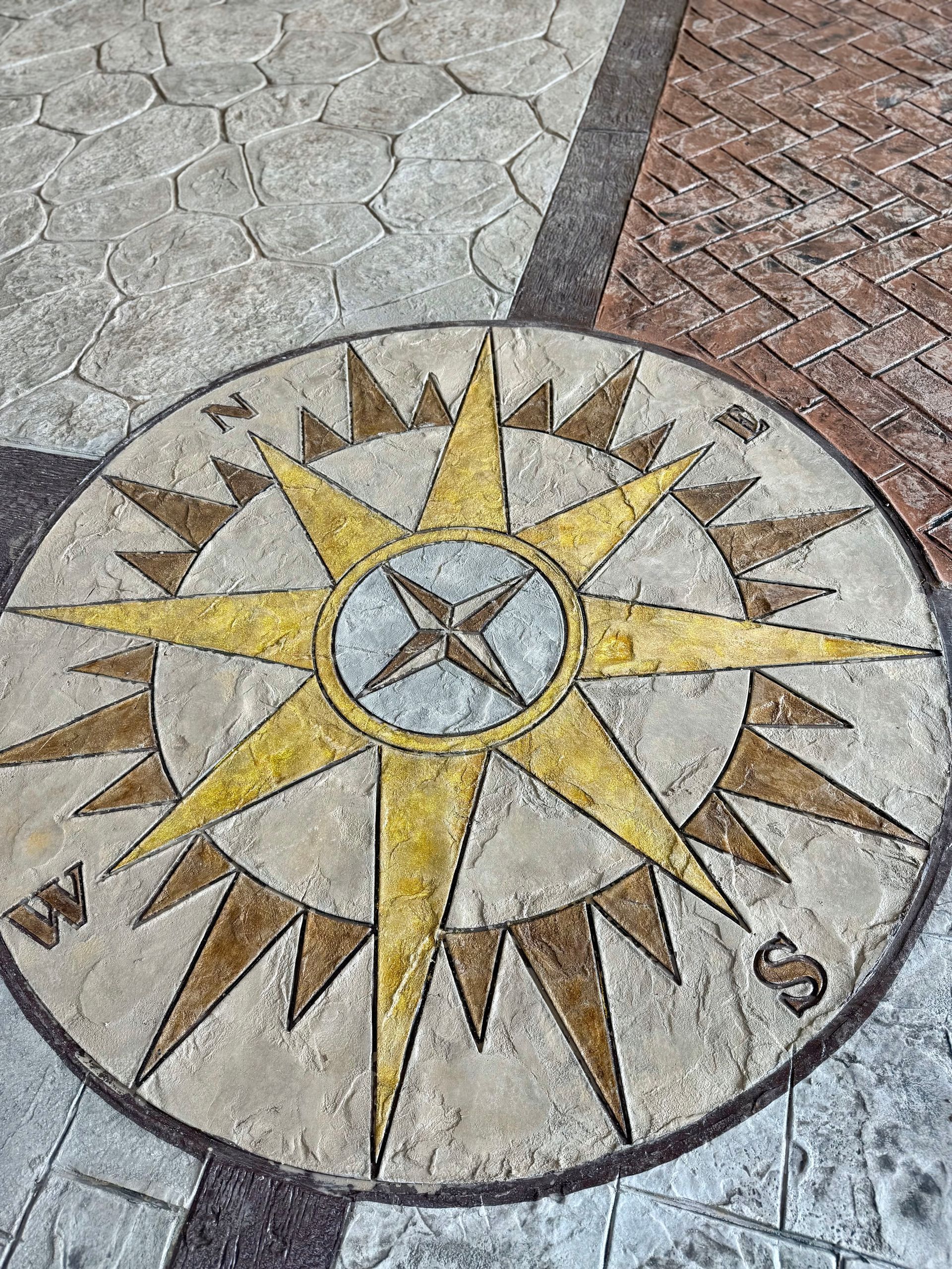 There is a compass on the ground that says north , south , east and west.