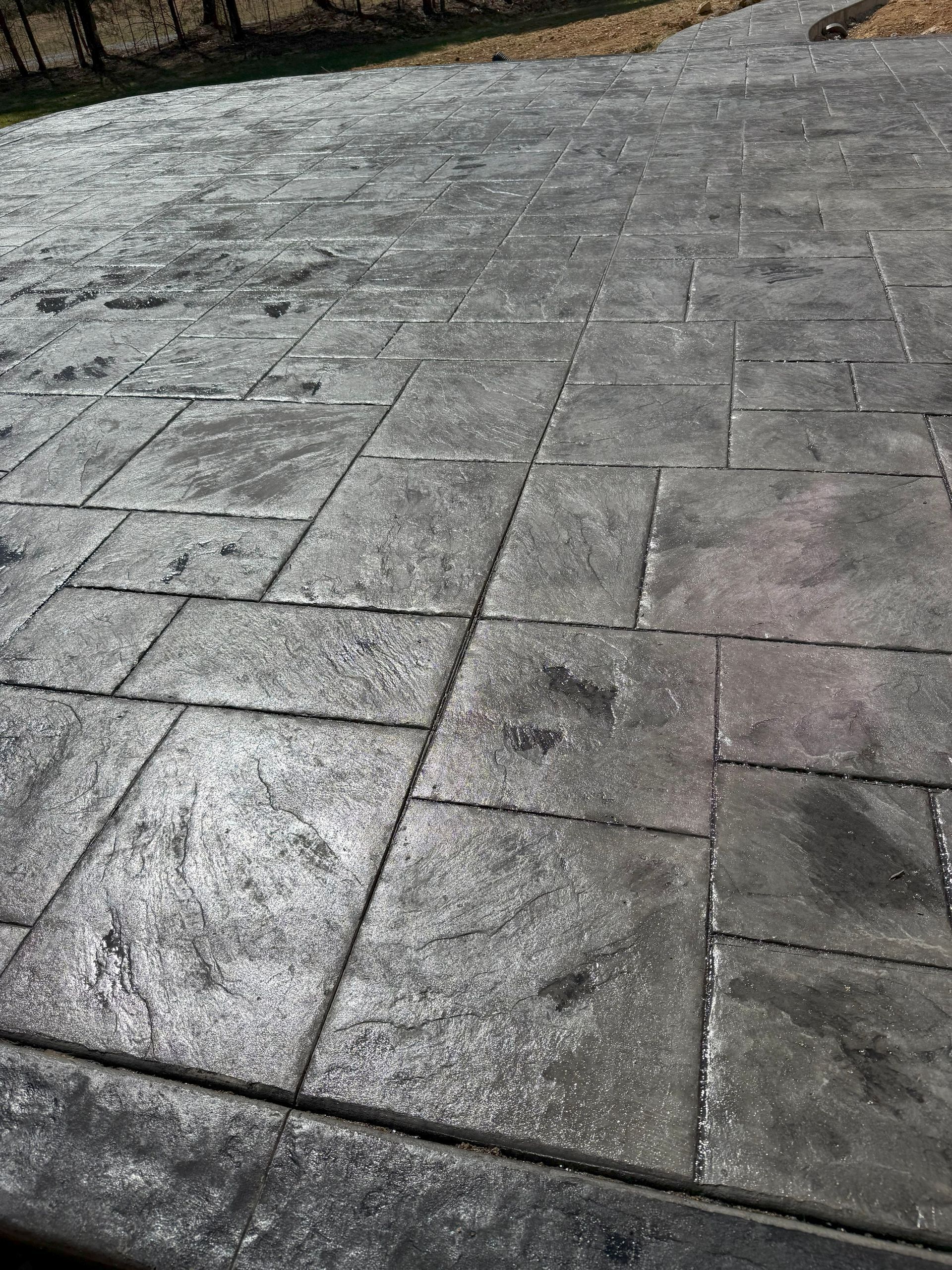 A close up of a concrete driveway with a pattern of squares.