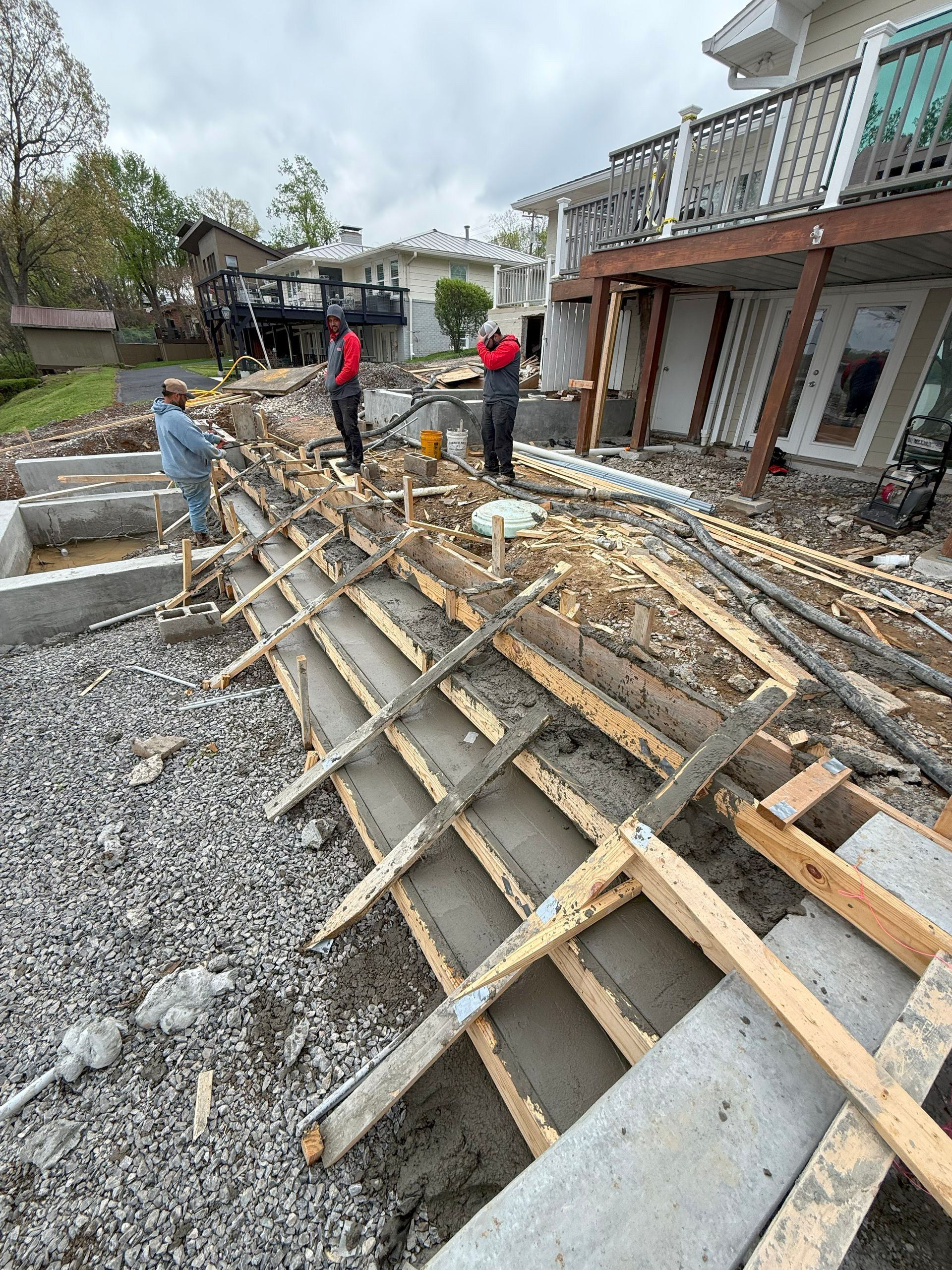 A group of men are working on a concrete wall in front of a house.