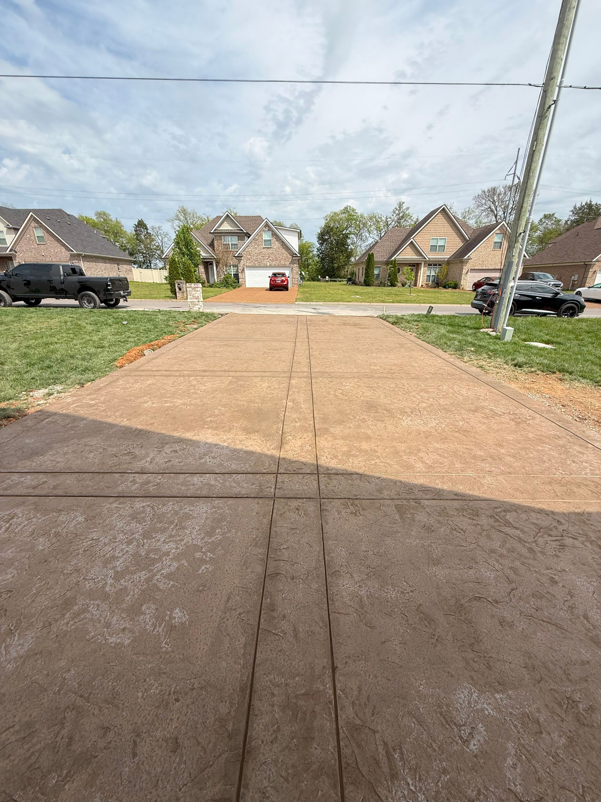 A driveway in a residential area with a lot of cars parked on the side of it.