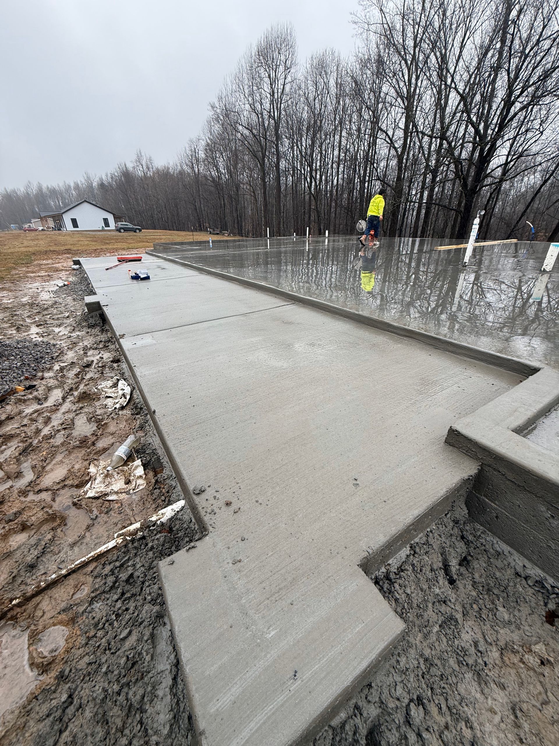 A concrete walkway is being built in a field with trees in the background.