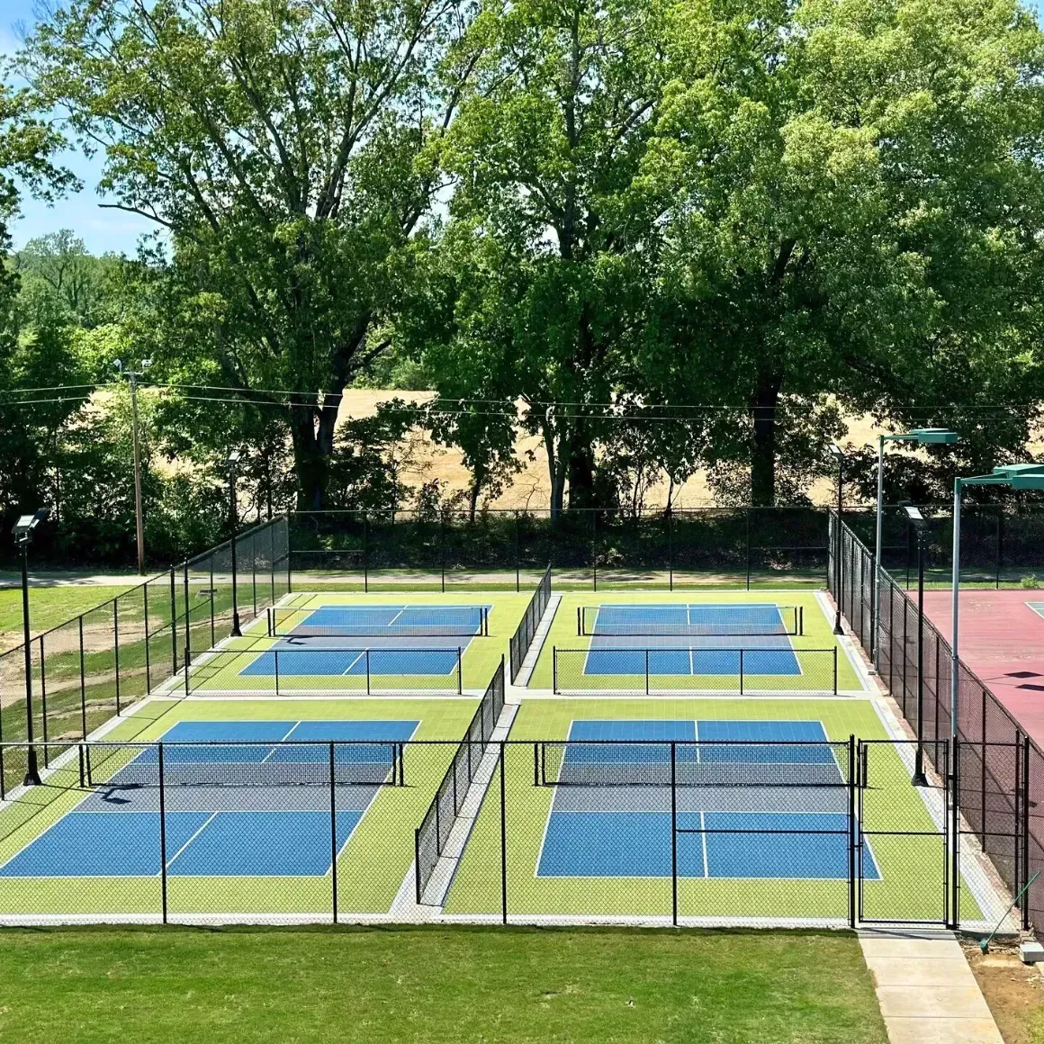 A tennis court with a fence around it and trees in the background.