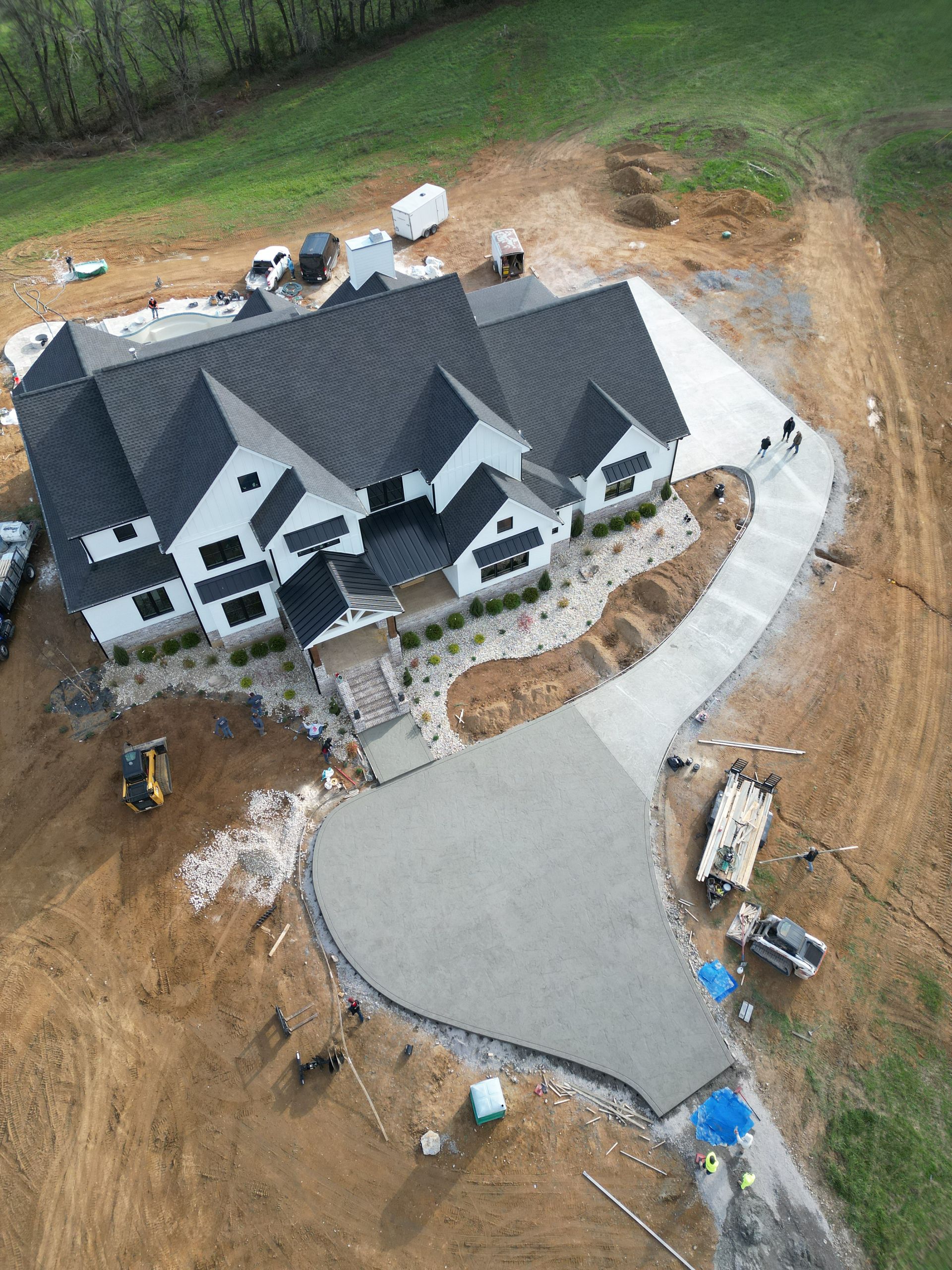 An aerial view of a large house under construction with a concrete driveway.