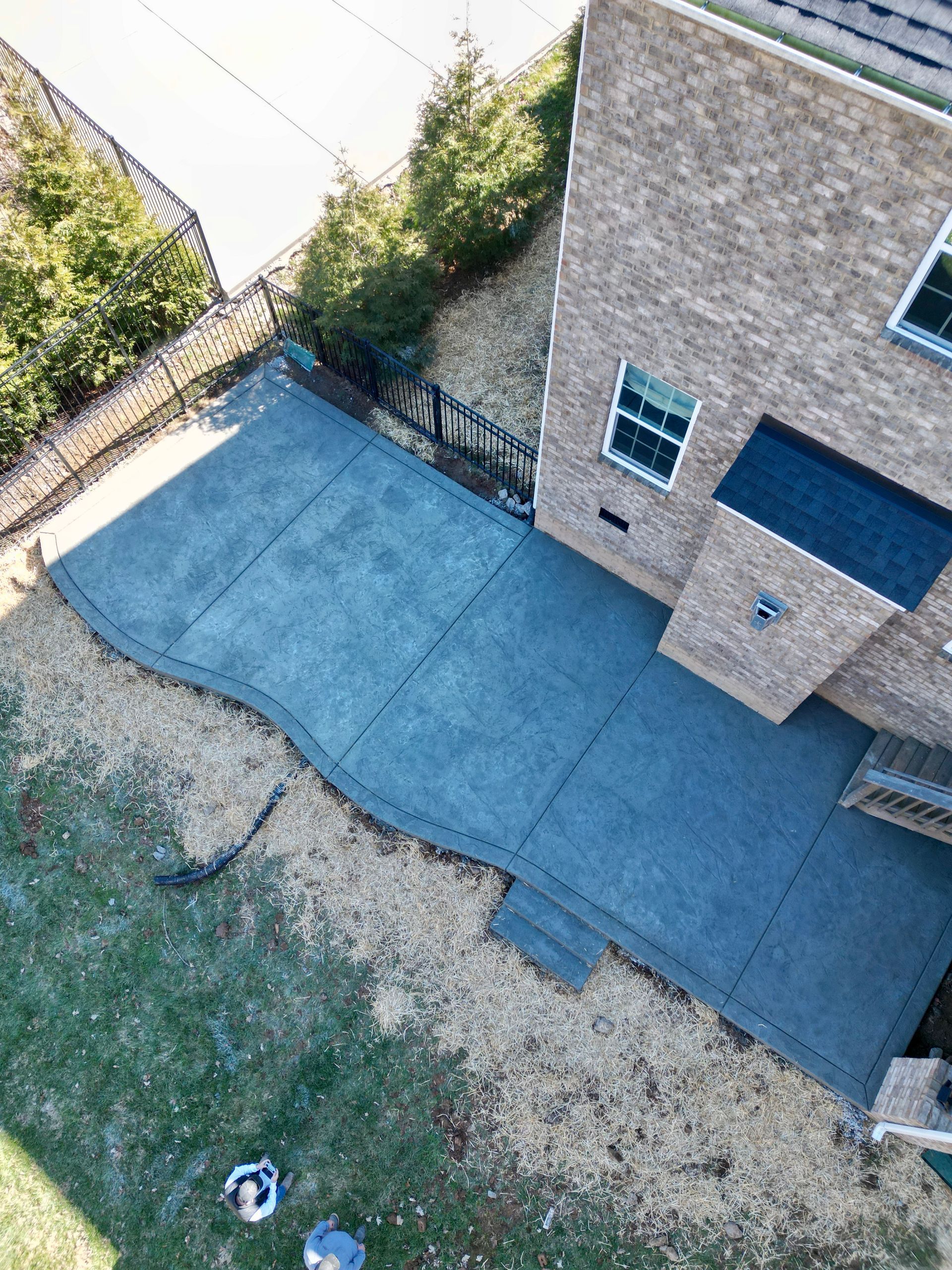 An aerial view of a brick house with a concrete driveway in front of it.
