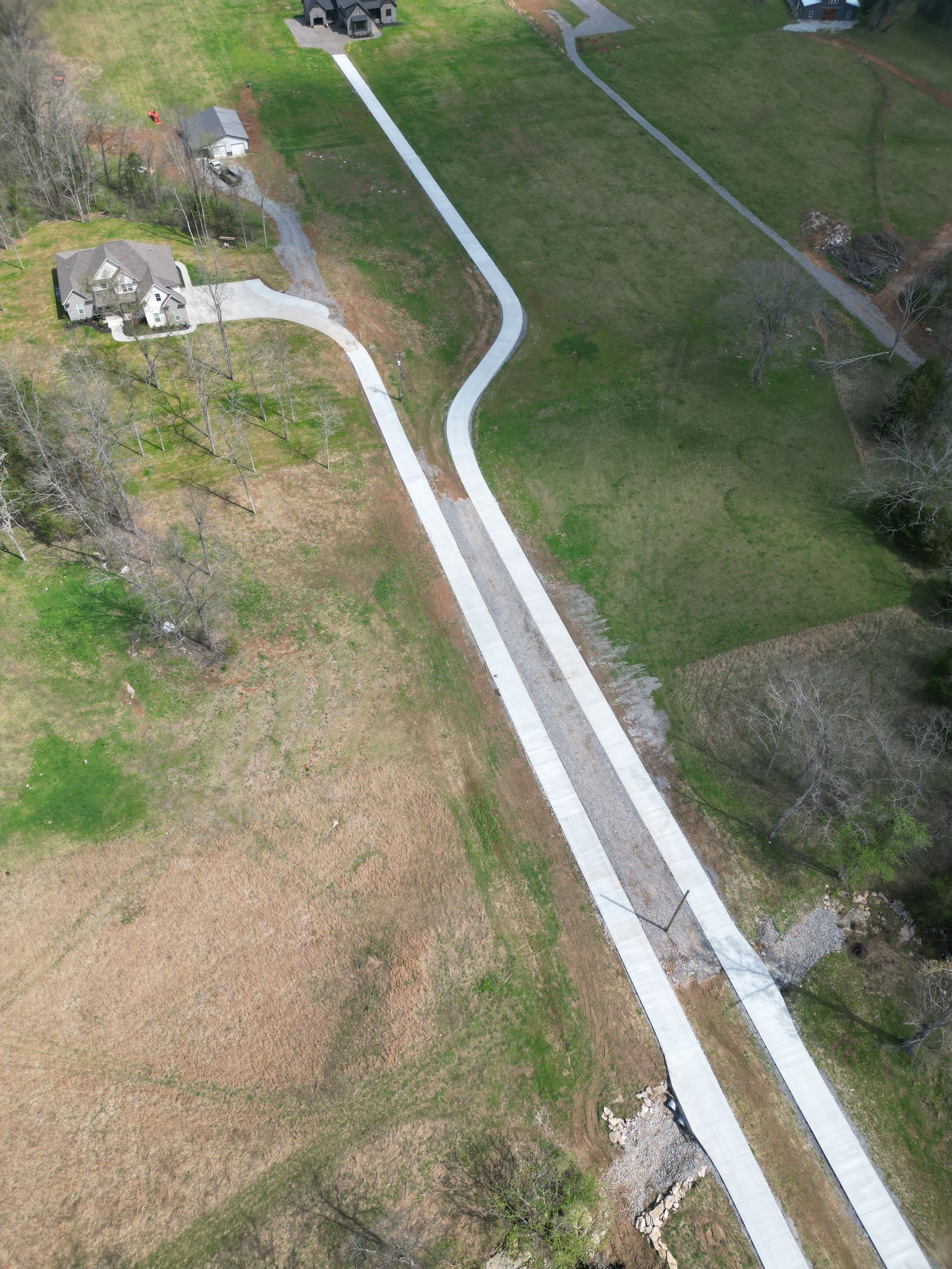 An aerial view of a driveway going through a grassy field.