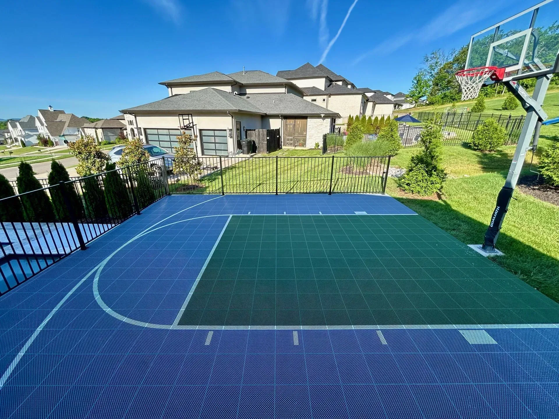 There is a basketball court in the backyard of a house.