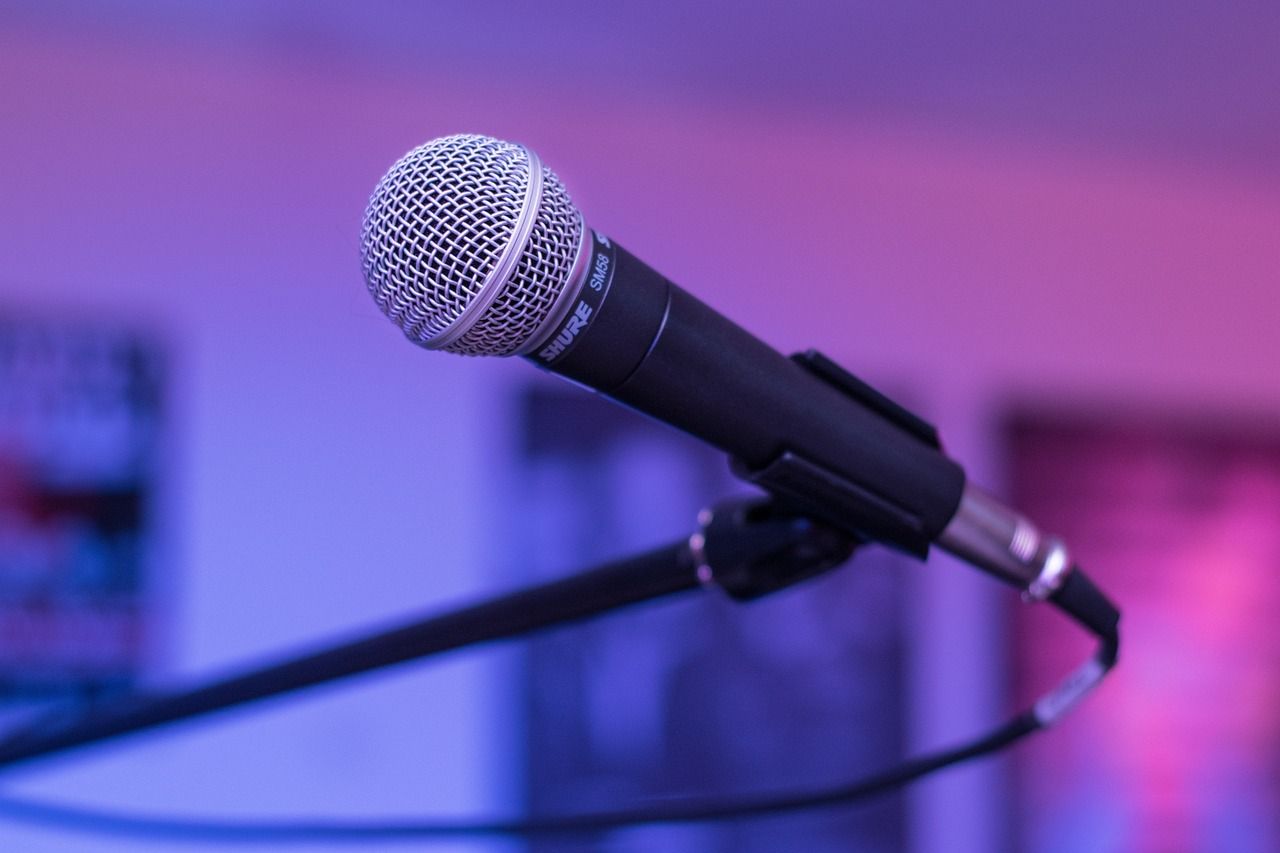 Microphone on a stand, close-up shot, illuminated by purple ambient lighting, with soft focus background.