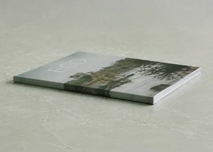 Minimalist Eco booklet with a gray-green landscape cover, lying on a light textured surface. Print and design at Total Creative, Auckland NZ