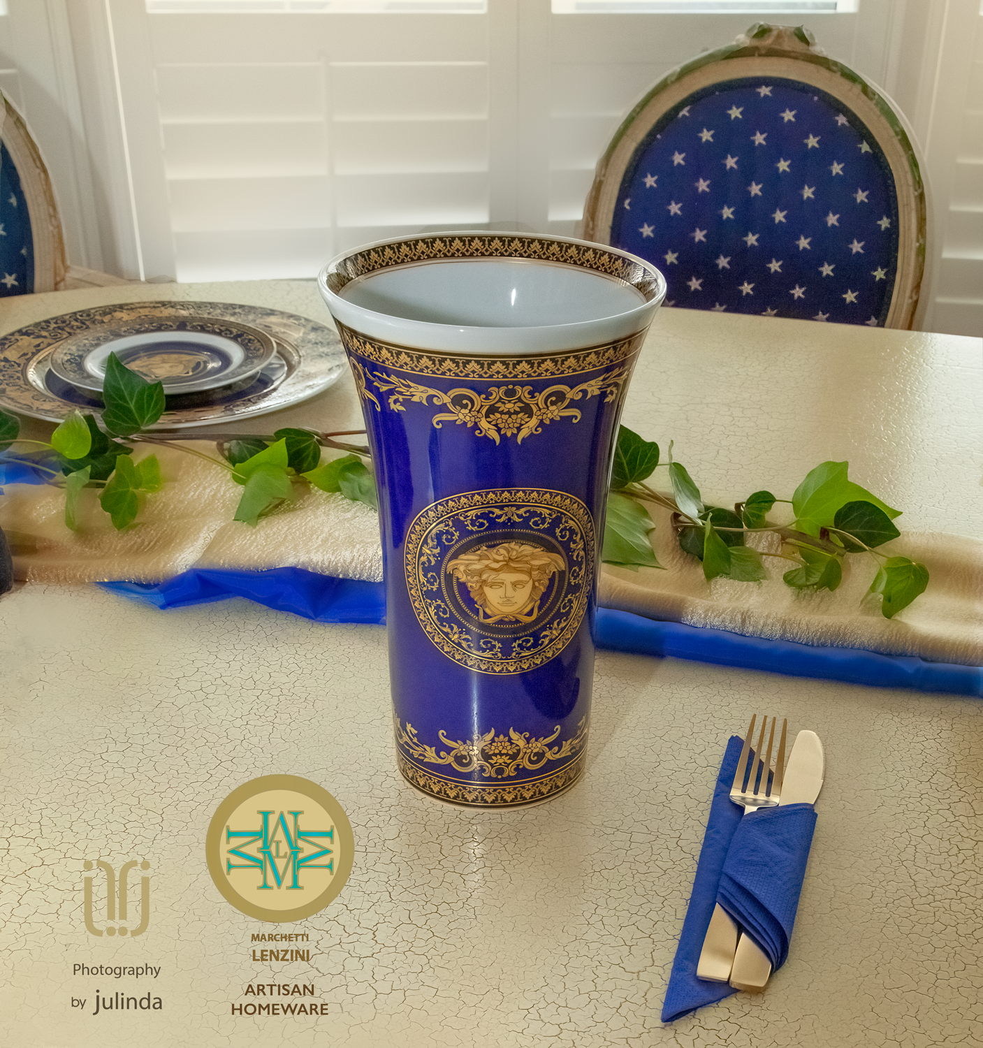 Versace vase on a table set for dining, blue and gold colors, next to a napkin with gold cutlery. Total Creative Auckland photographer.