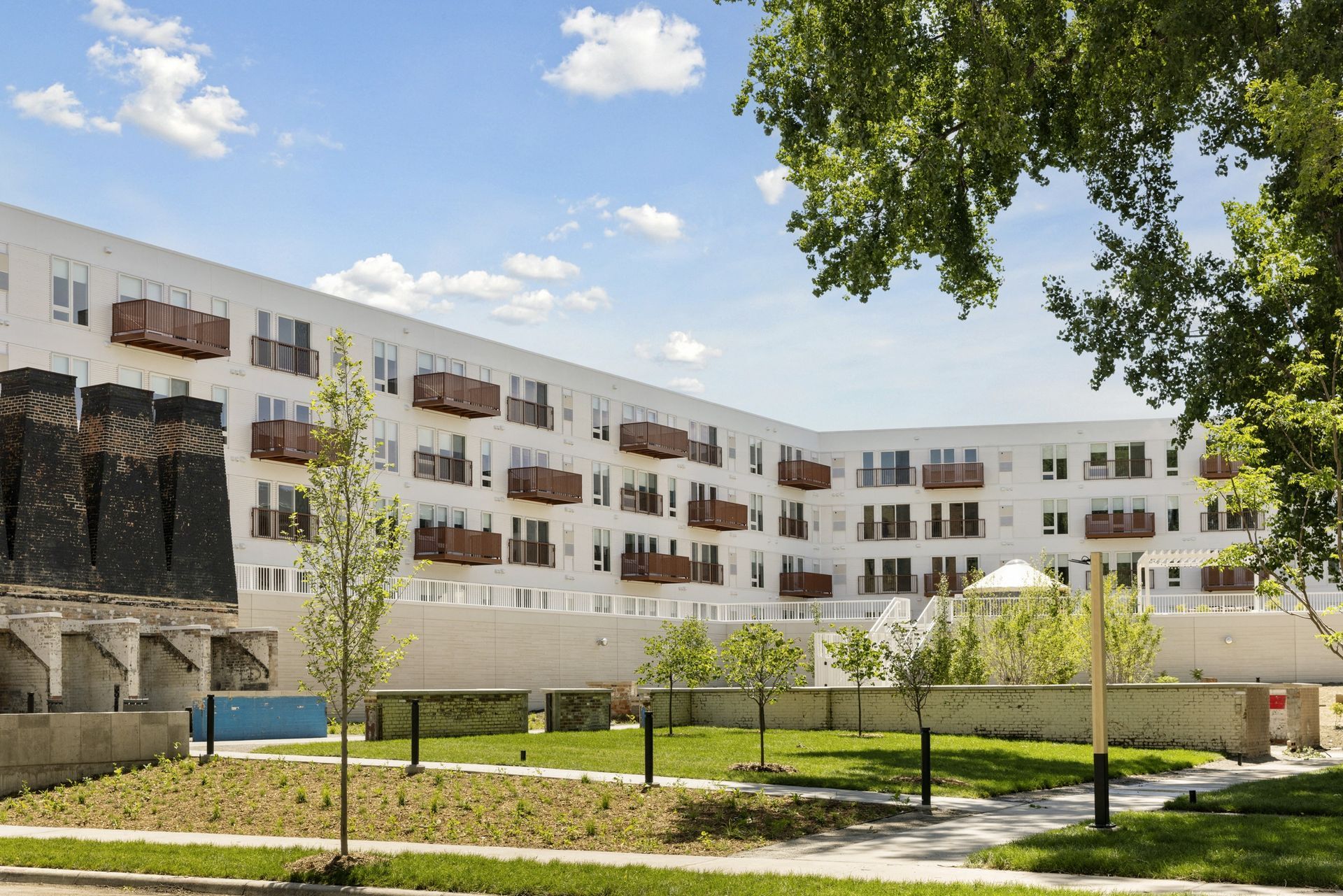 Exterior view of a white apartment building with brown balconies and a landscaped courtyard at Esox House in St. Paul, MN.