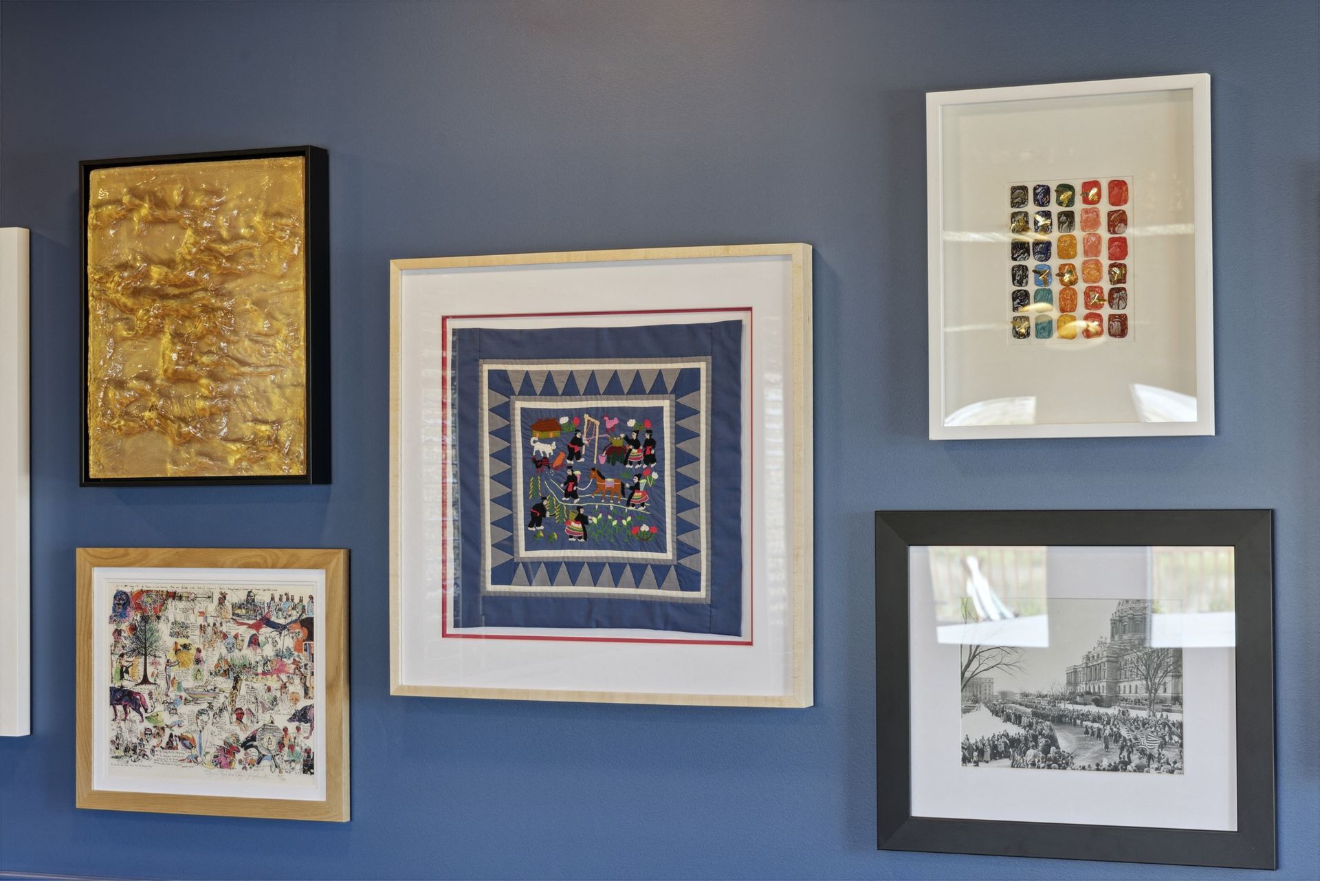 Blue wall with six framed artworks arranged in a gallery display at Esox House in St. Paul, MN.