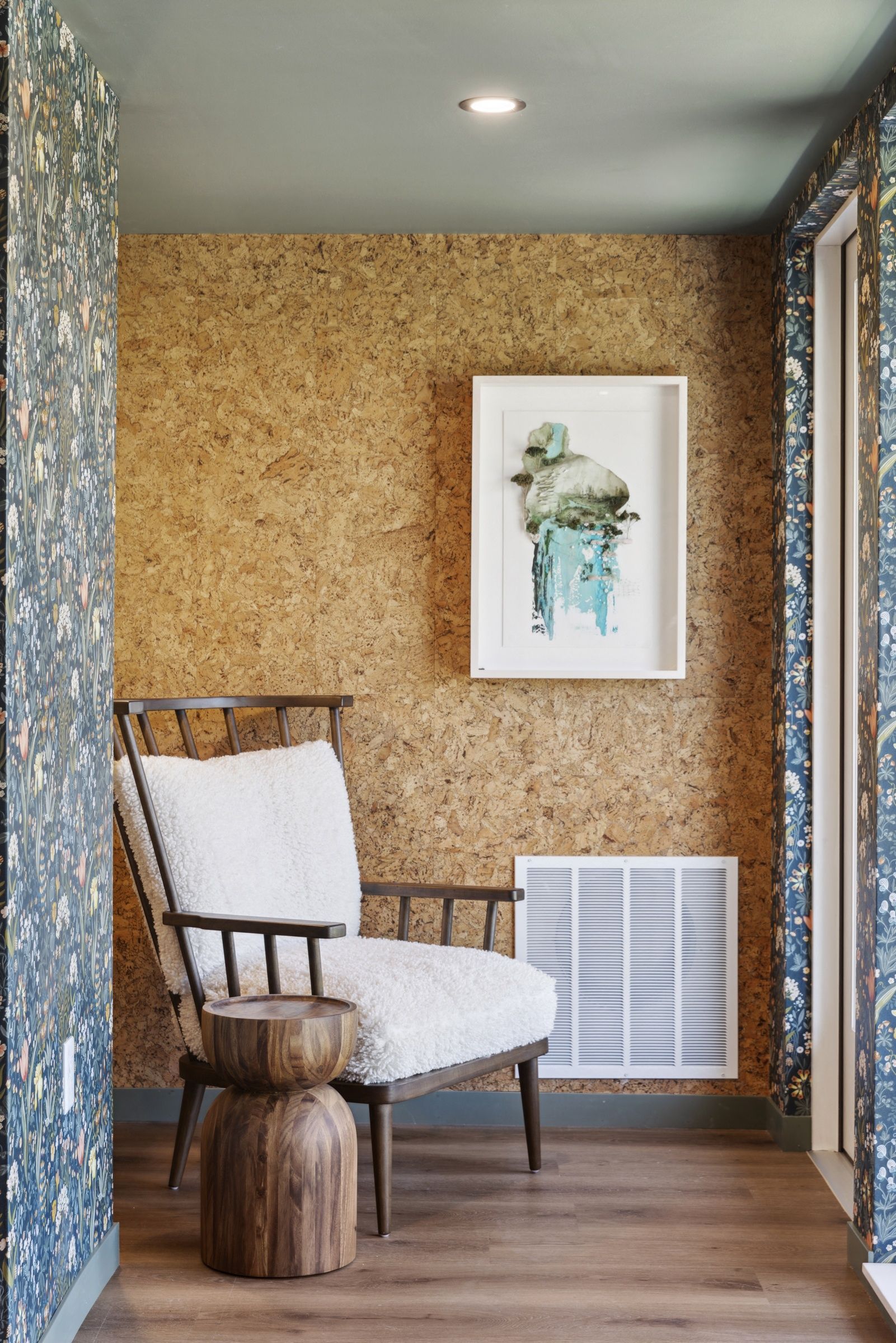 Interior corner with a wooden chair, white fluffy upholstery, cork wall, and framed art at Esox House in St. Paul, MN.