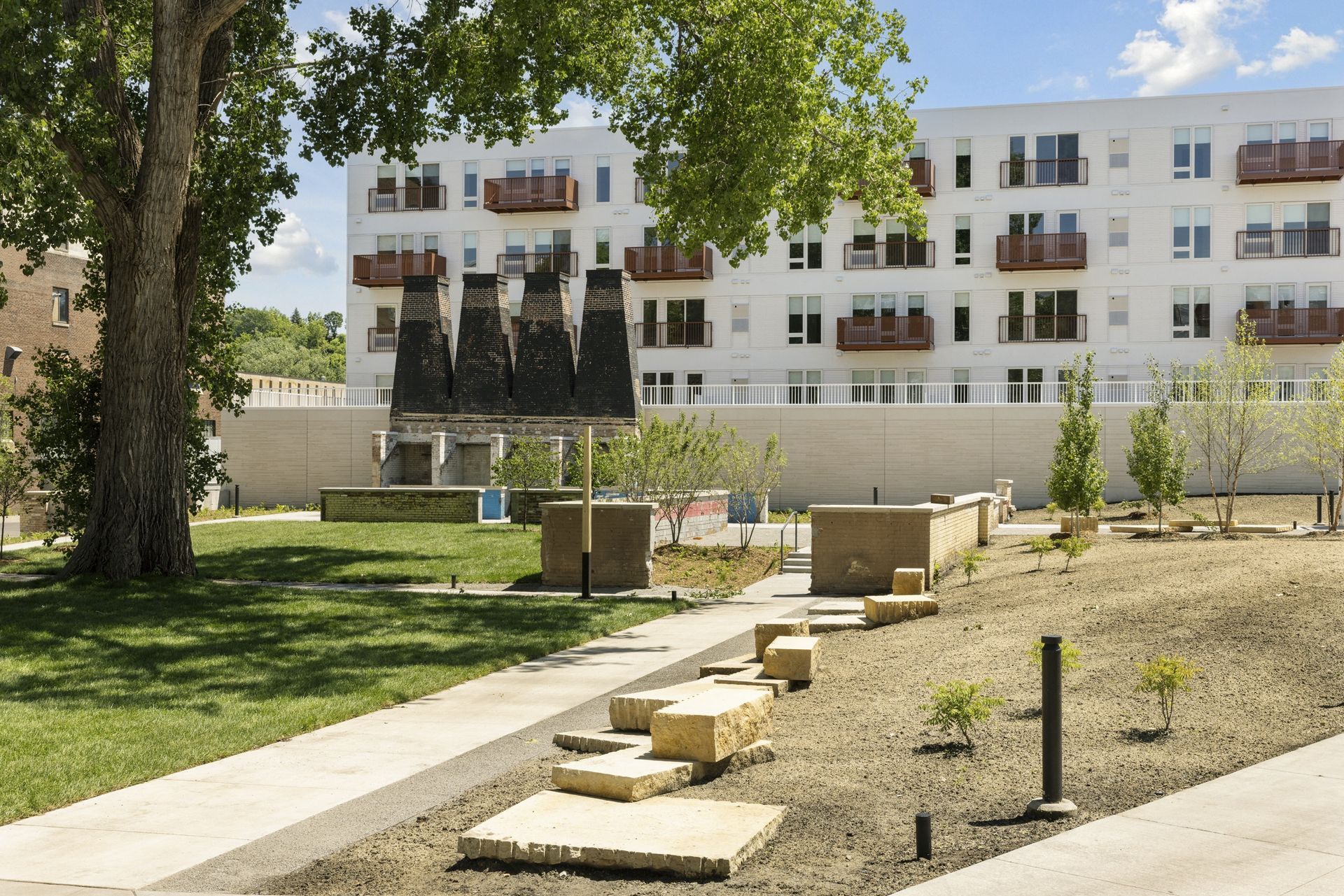 Exterior view of a white apartment building with balconies and a landscaped courtyard at Esox House in St. Paul, MN.