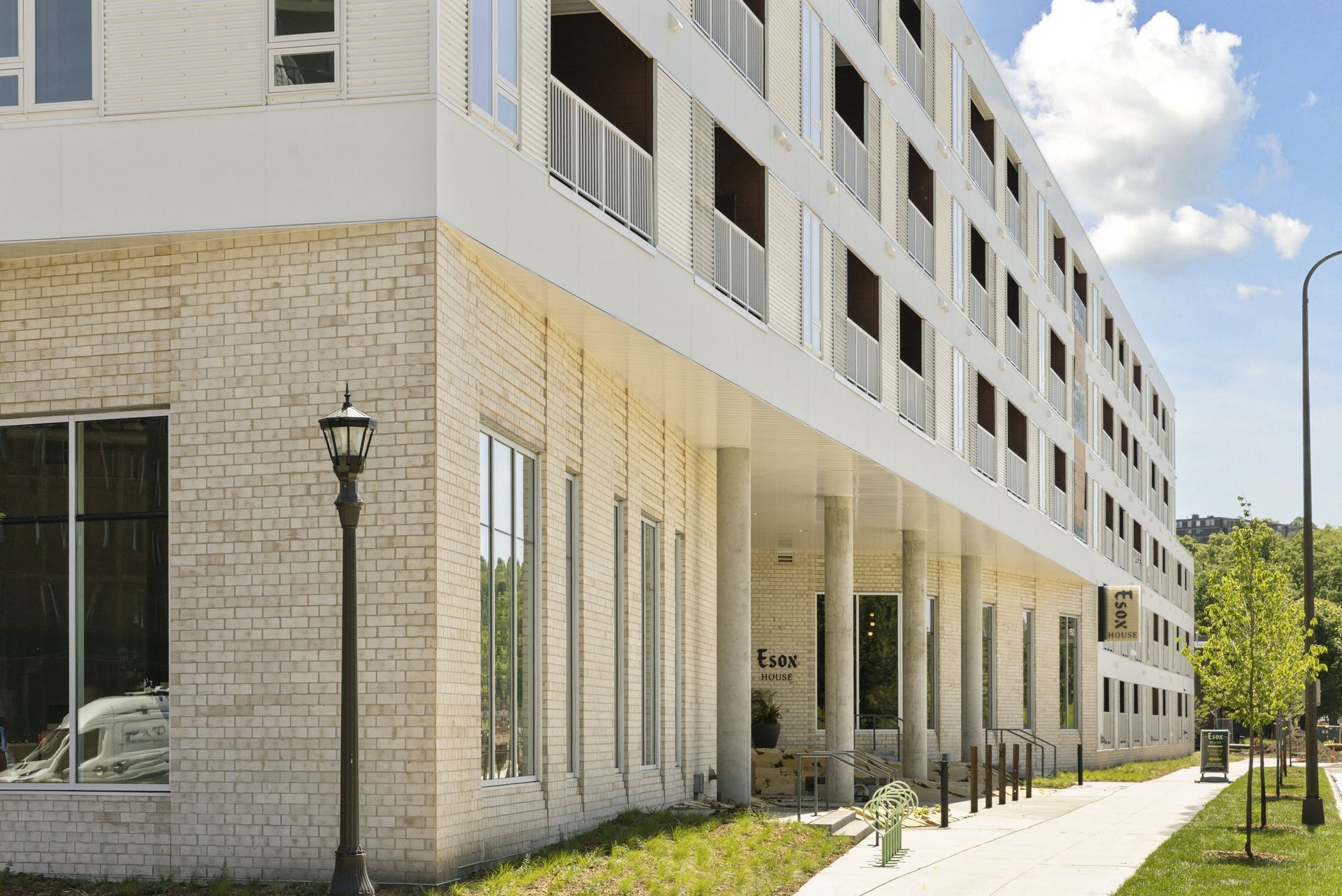 Exterior view of a multi-story apartment building with brick base and row of balconies at Esox House in St. Paul, MN.