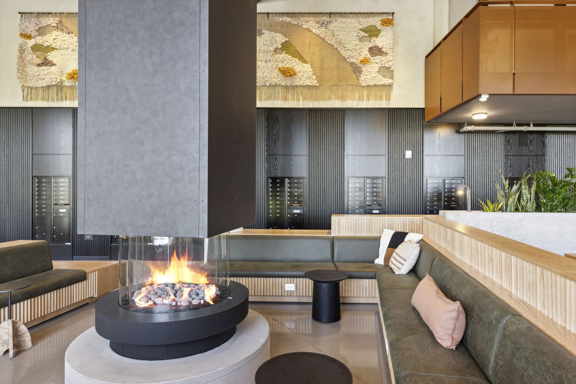 Cozy lounge with fireplace, built-in seating, art, and modern design. Dark gray fireplace contrasts light wood and green upholstery.
