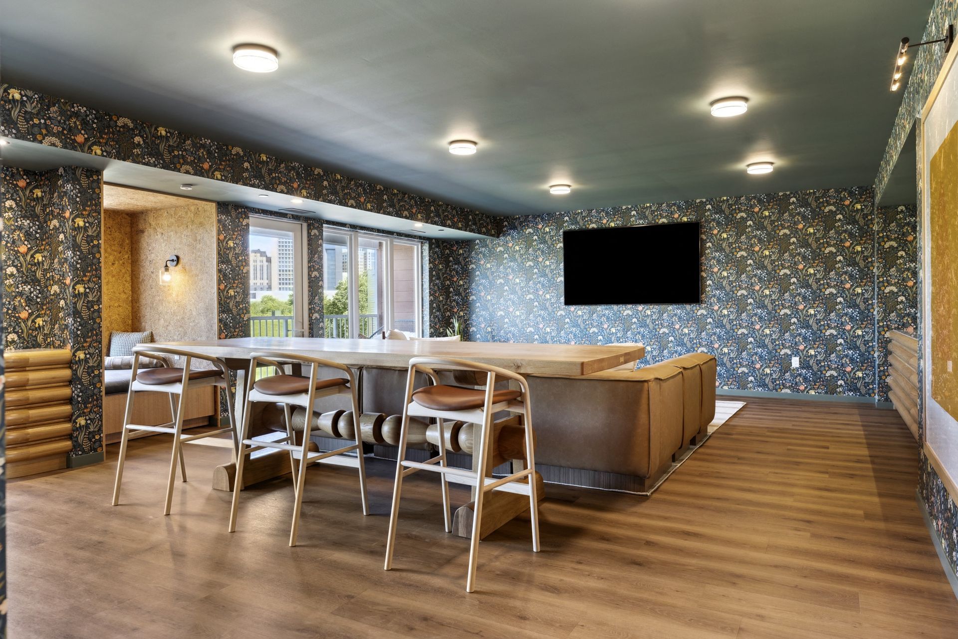 Spacious room with long table and chairs, couch, and large TV; walls are patterned with gray, black, and gold.