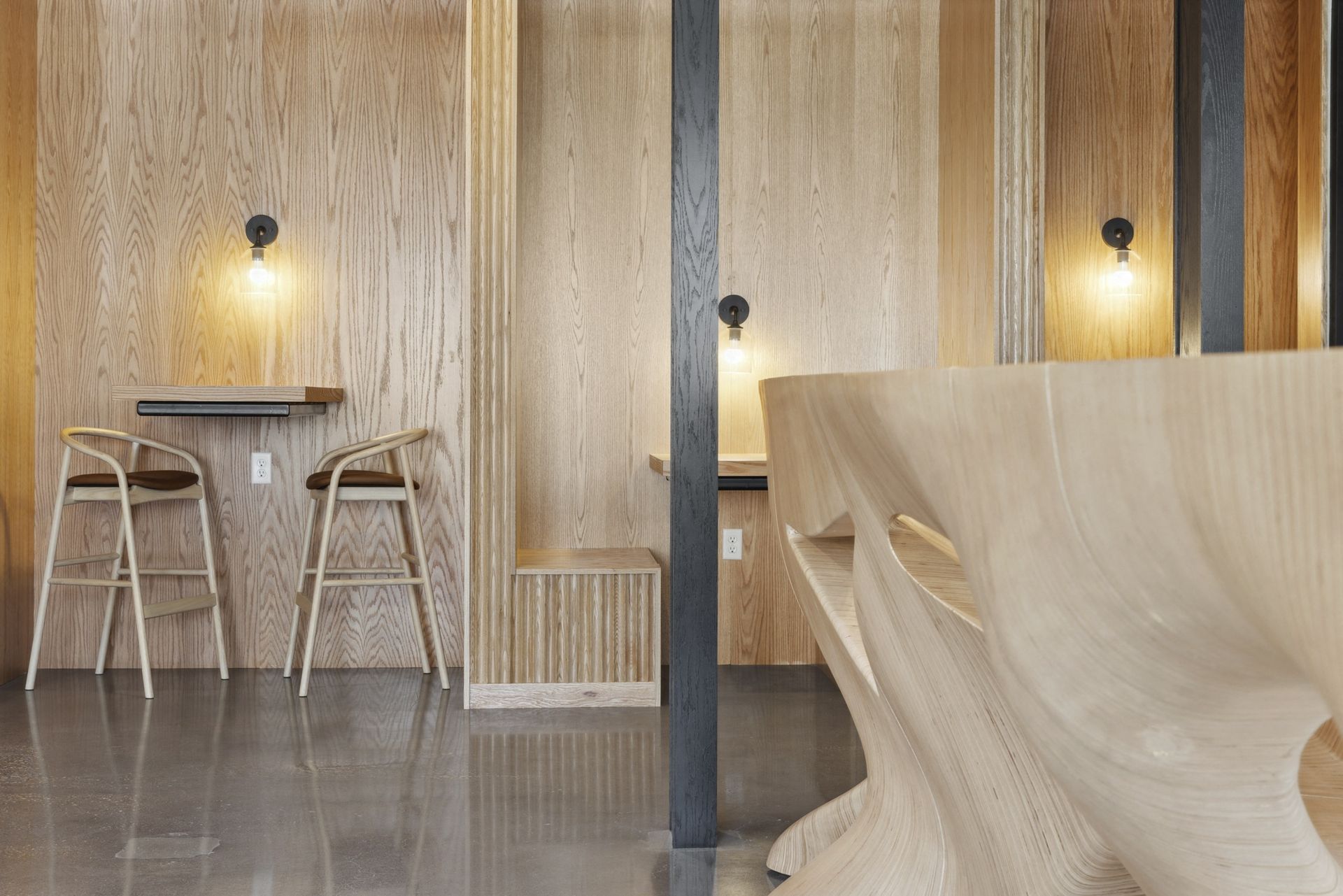Wood-paneled communal lounge with bar-height tables, stools, and warm wall lights at Esox House in St. Paul, MN.