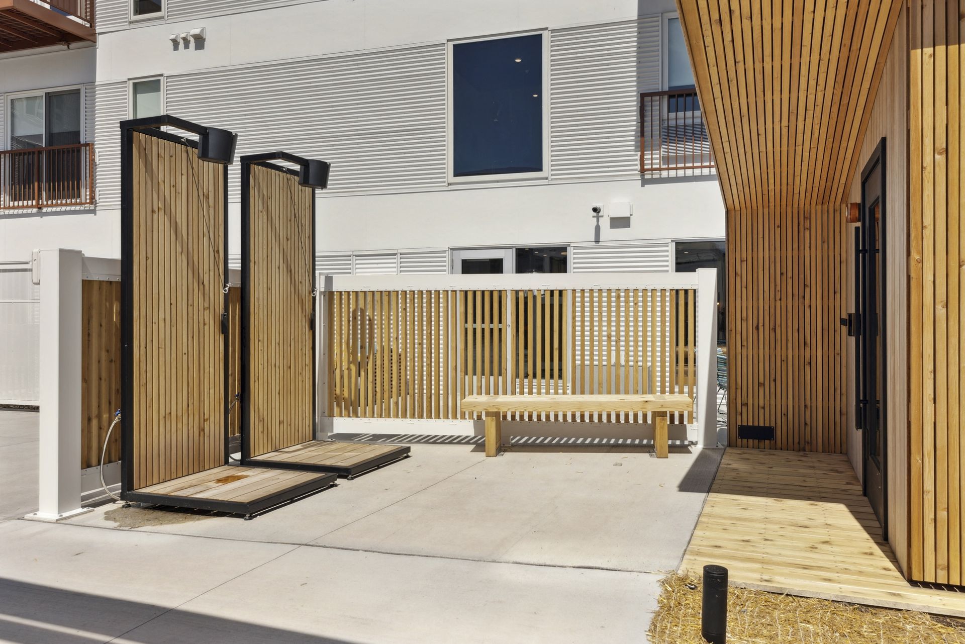 Exterior courtyard with wooden gates, bench, and modern building facade at Esox House in St. Paul, MN