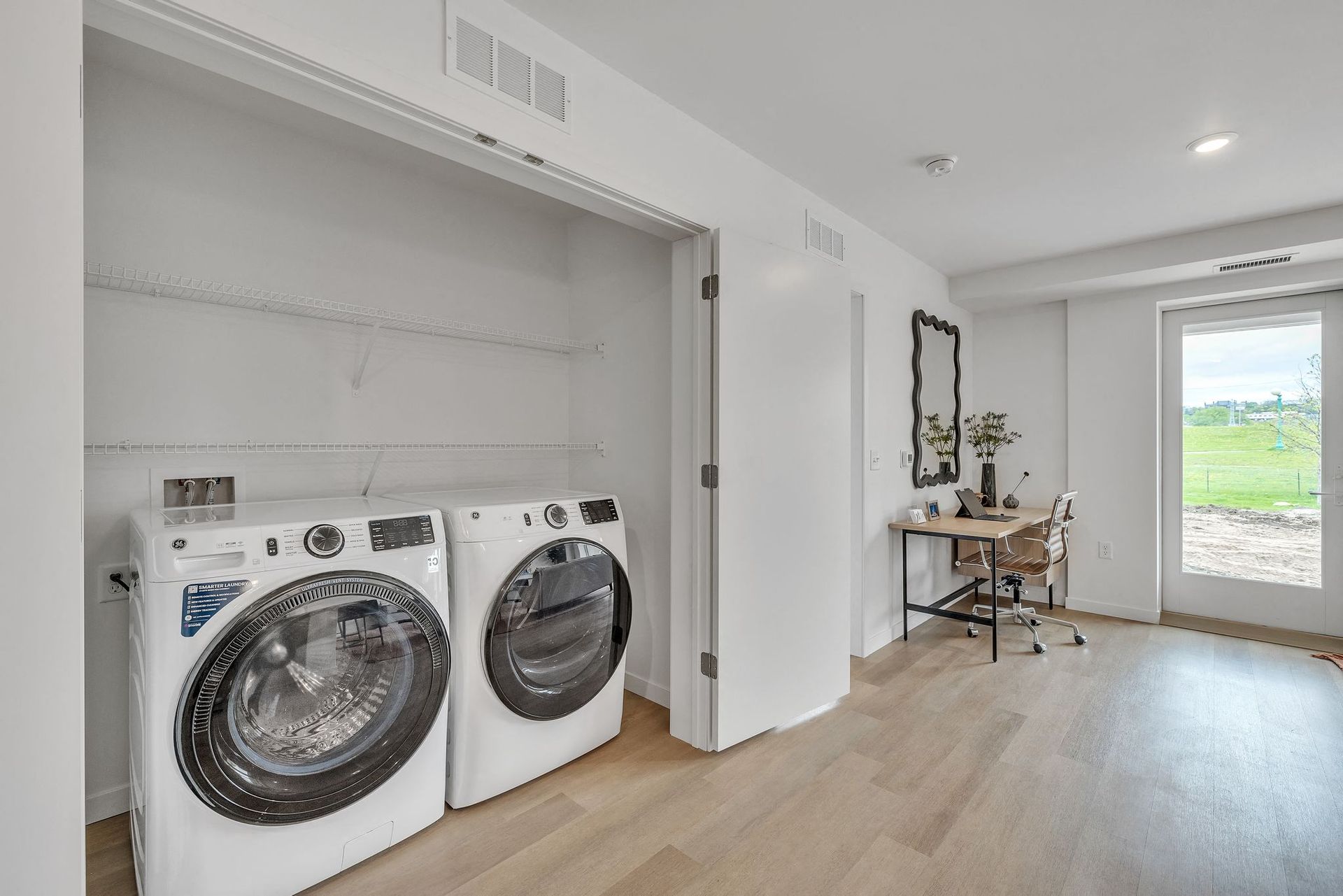 Laundry closet with front-loading washer and dryer beside a small desk at Esox House in St. Paul, MN.