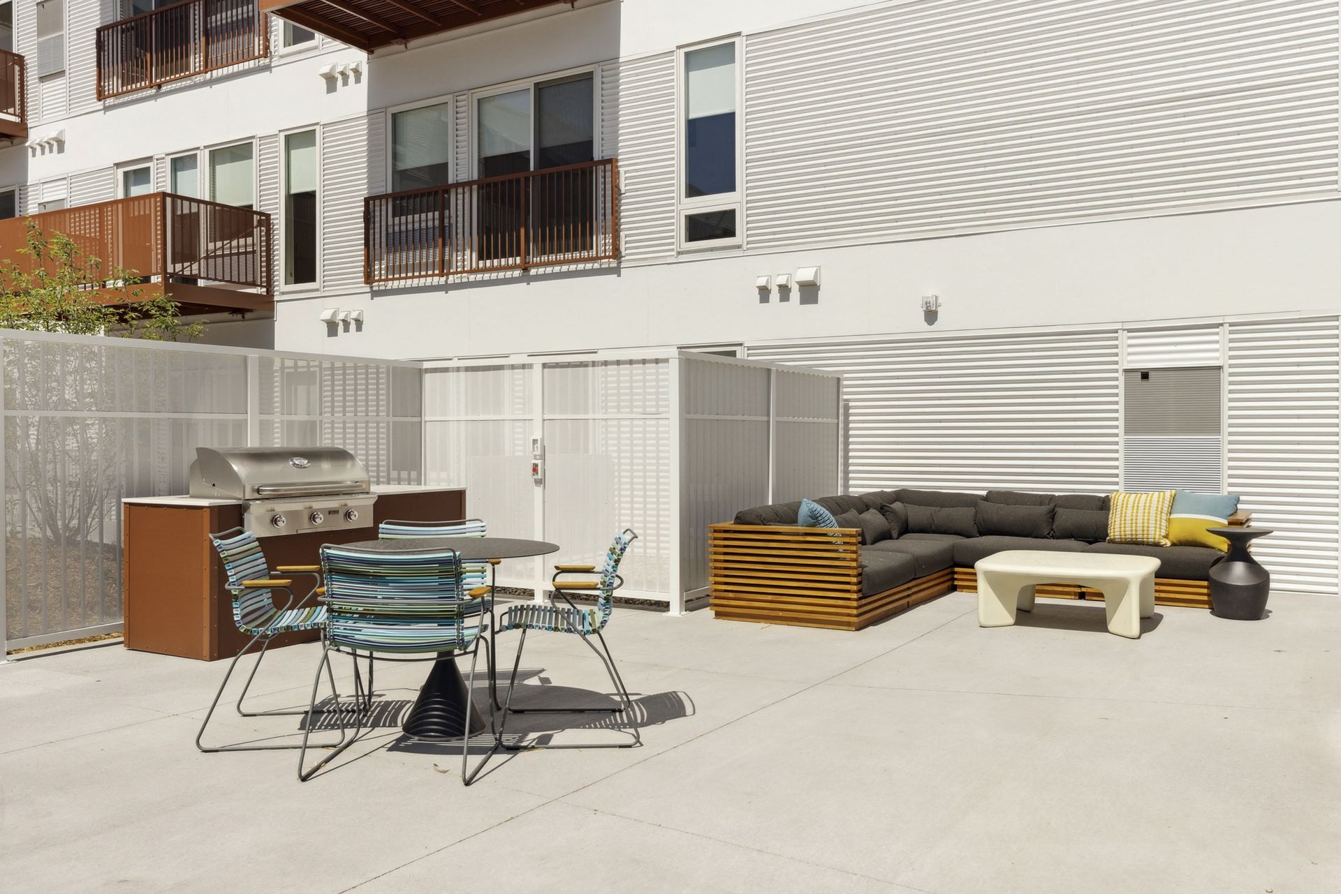 Outdoor communal patio with a stainless grill, round table, and colorful seating at Esox House in St. Paul, MN.