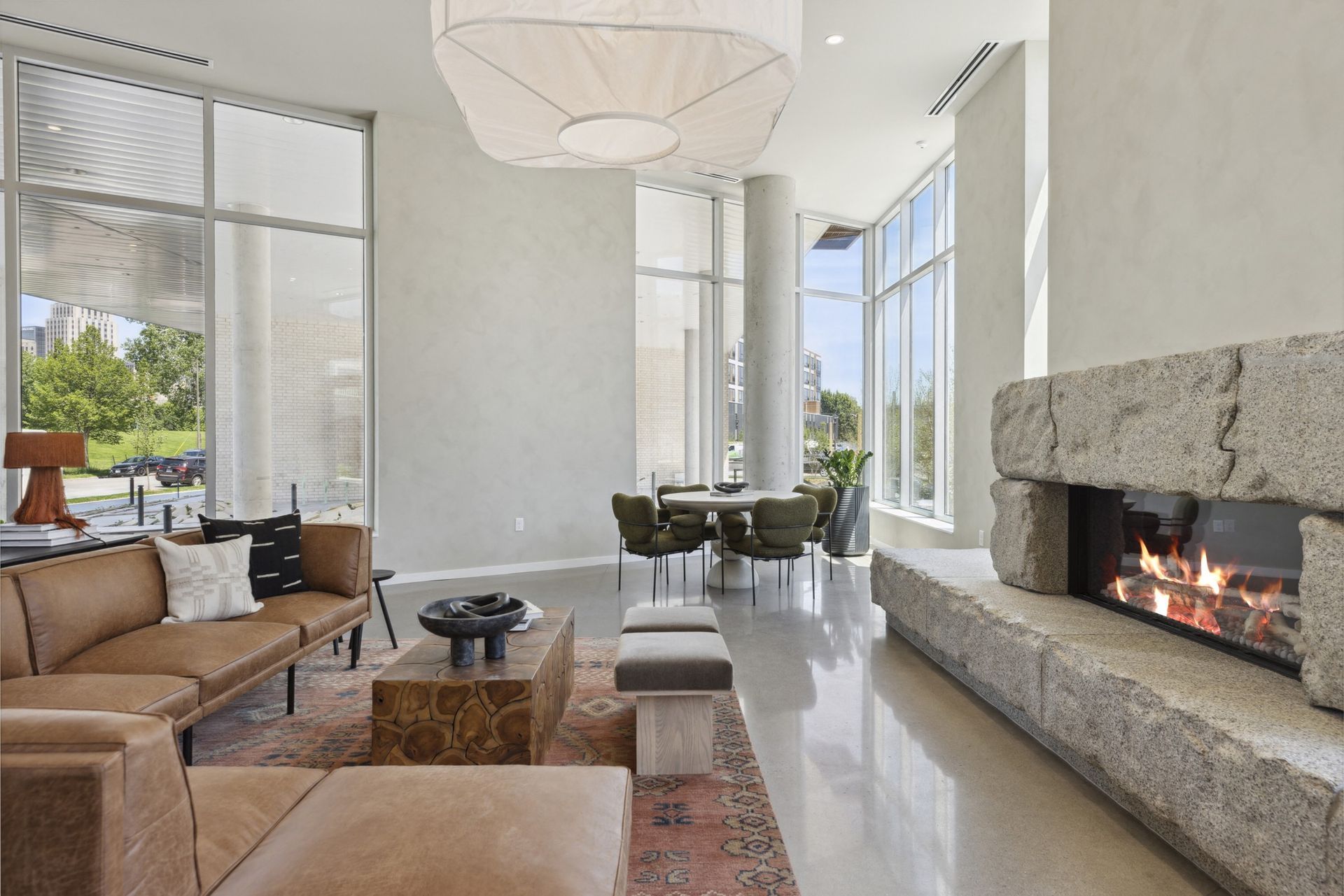 Modern community lounge with stone fireplace, sofa seating, and large windows at Esox House in St. Paul, MN.
