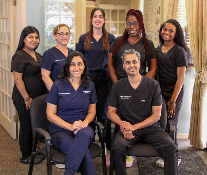 Group of dental office staff, smiling, posing together inside the office.