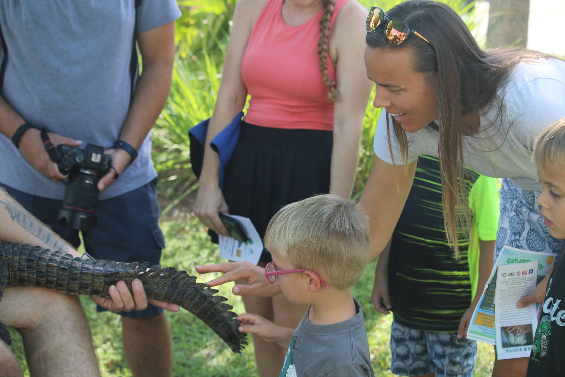 Children petting the tail of a crocodile