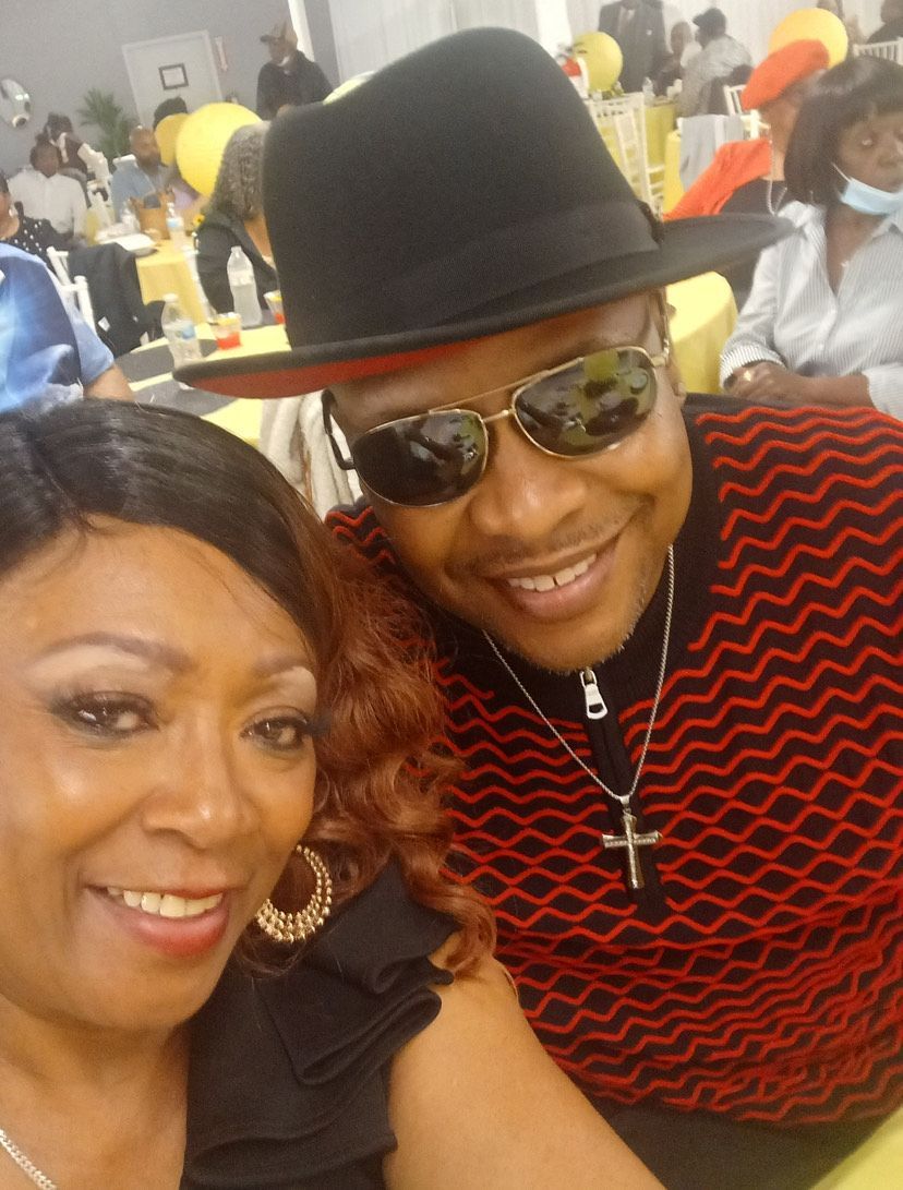 A man wearing a hat and sunglasses is posing for a picture with a woman