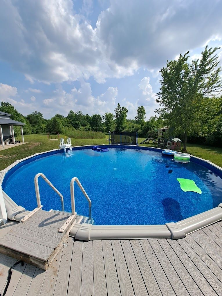 A large swimming pool is surrounded by trees and a deck.