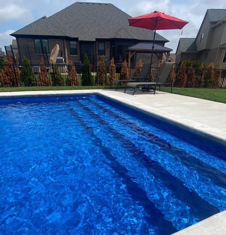A swimming pool with a red umbrella in front of a house