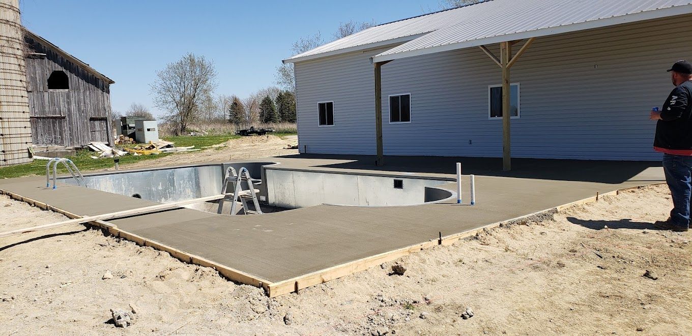 A man is standing in front of a swimming pool under construction.