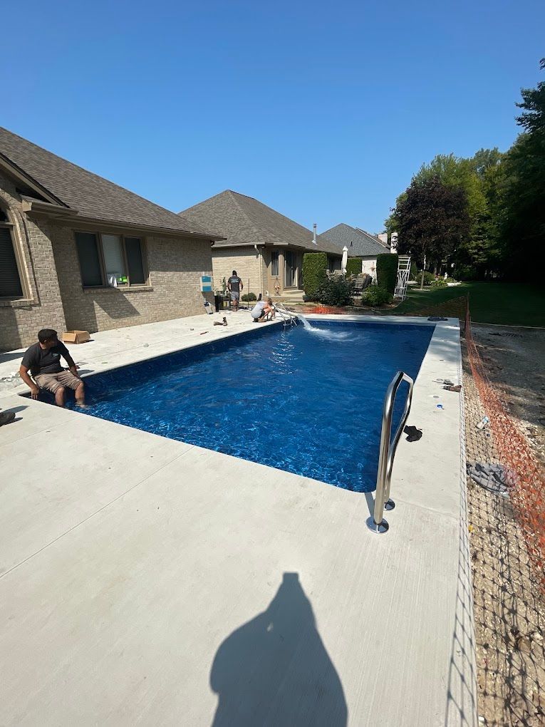 A man is sitting on the edge of a large swimming pool.