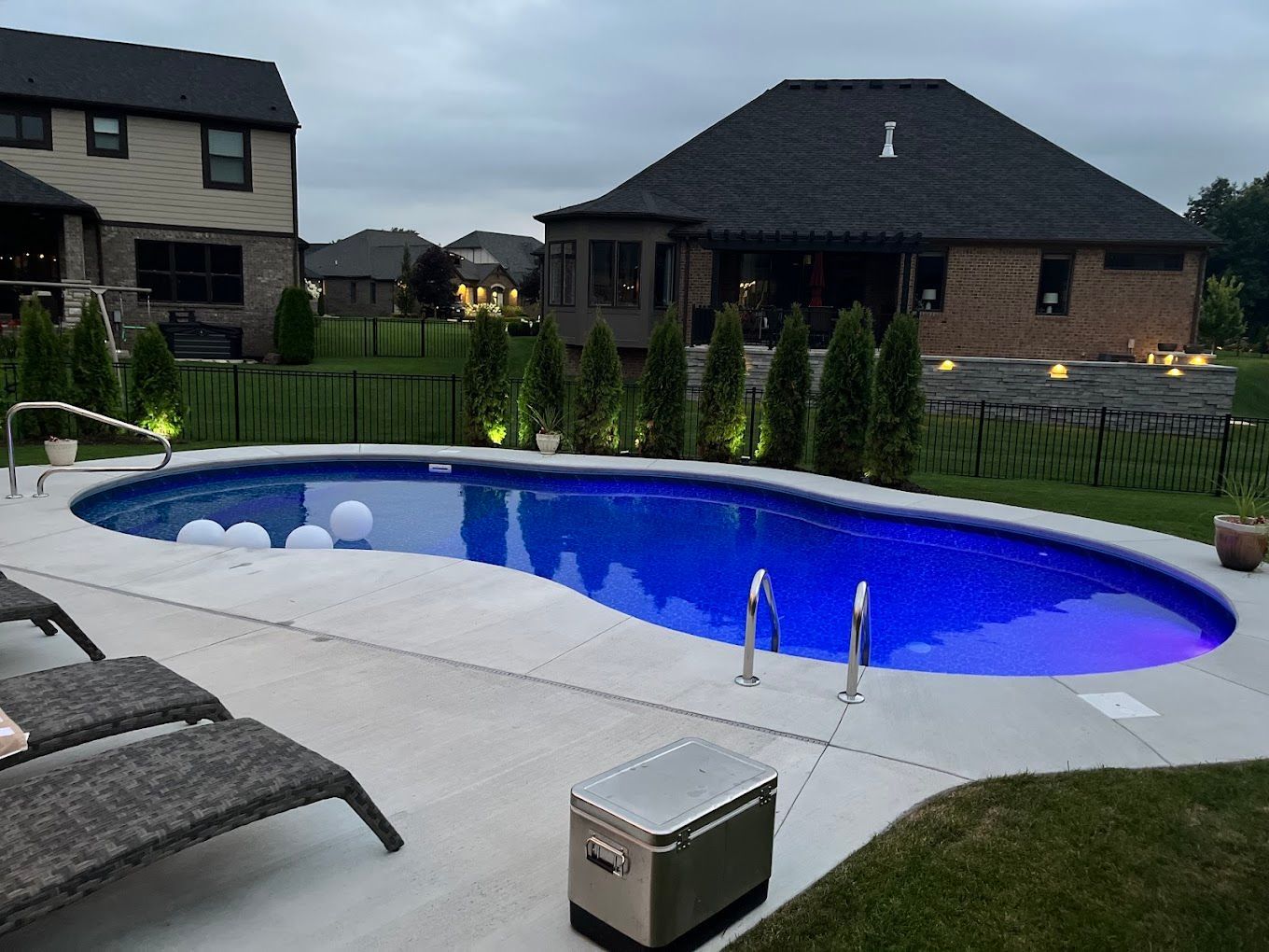 A large swimming pool in a backyard with a house in the background.