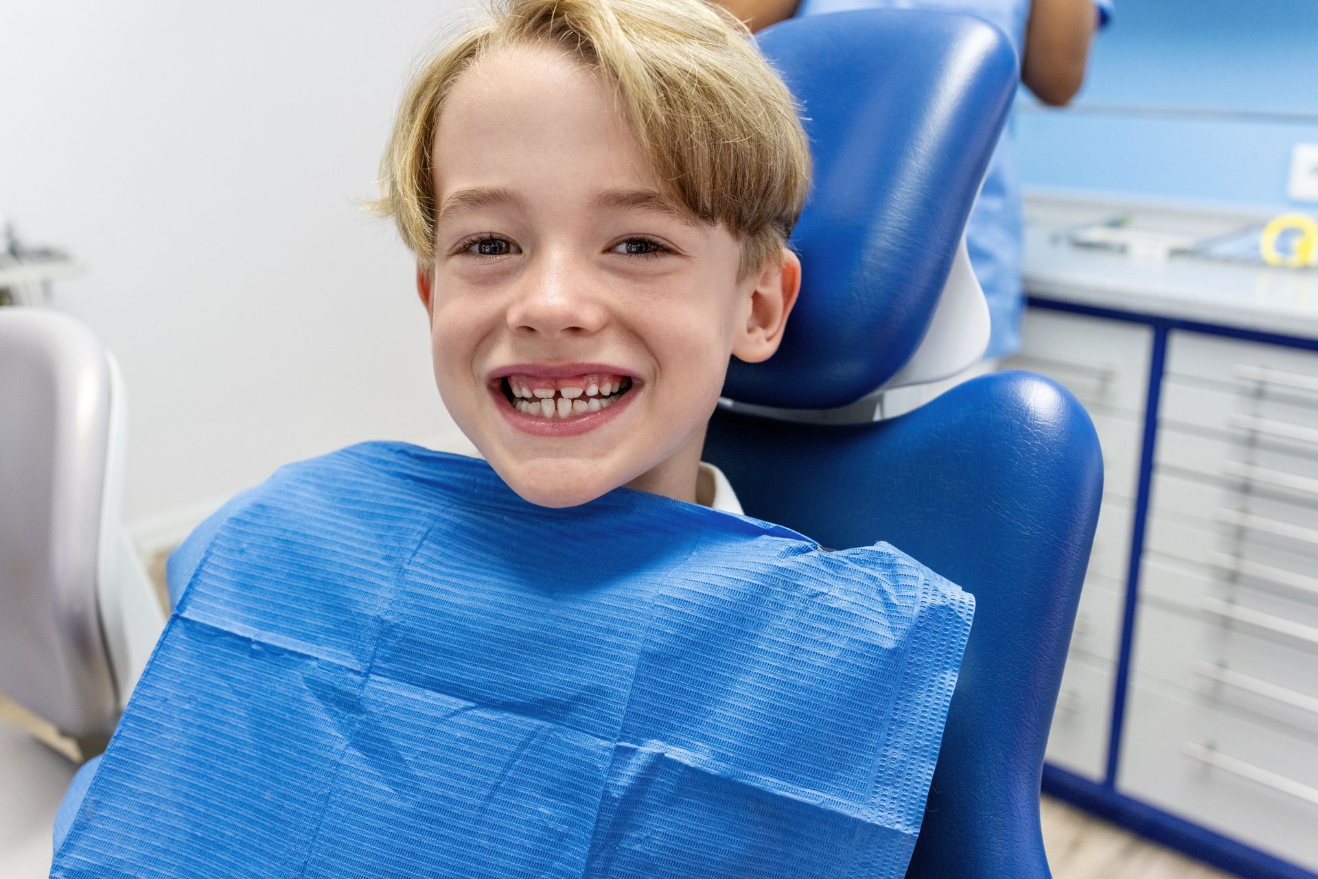 A confident child smiling proudly in a dental chair after a gentle, friendly check-up.