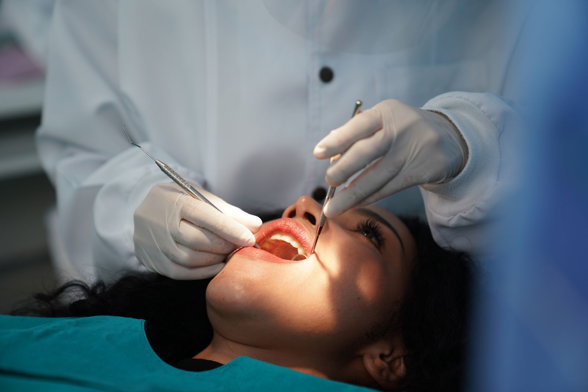 Dental centre performing oral exam with patient lying back and dentist using mirror tool.