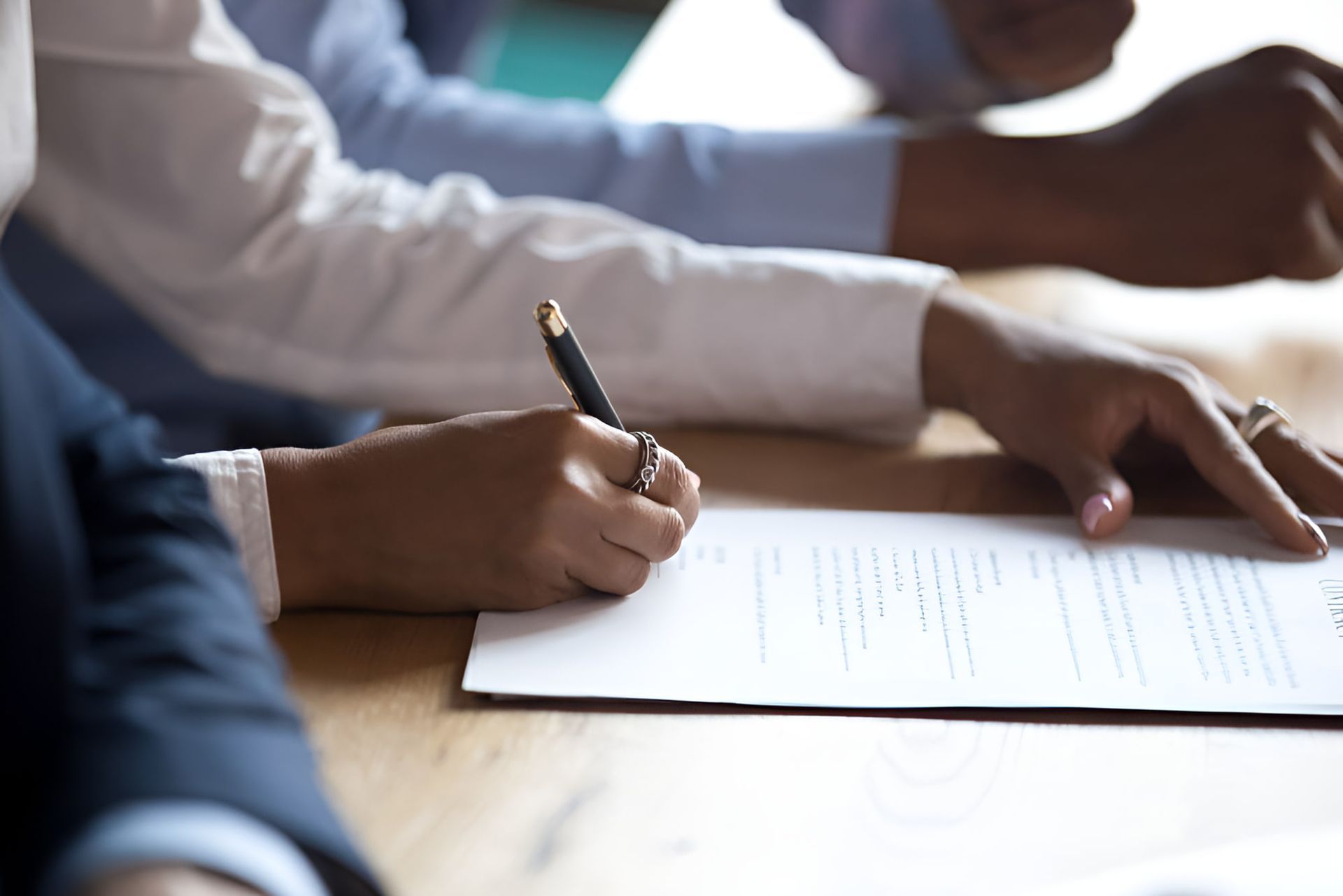 A Group Of People Are Sitting At A Table Signing A Document — De Silva Hebron In Darwin City, NT