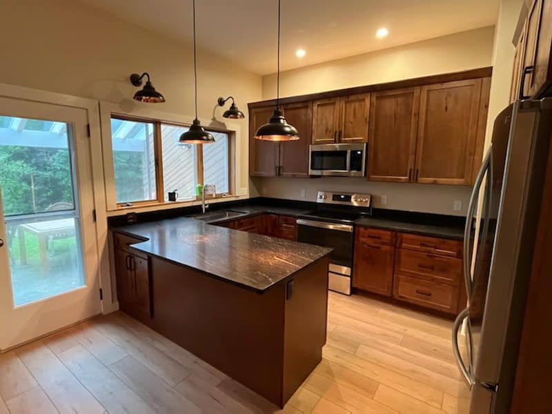 A kitchen with wooden cabinets , granite counter tops , stainless steel appliances and a large island.