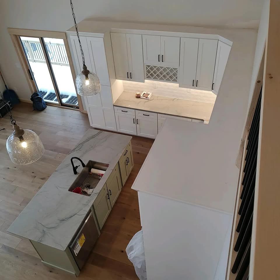 An aerial view of a kitchen with white cabinets and marble counter tops